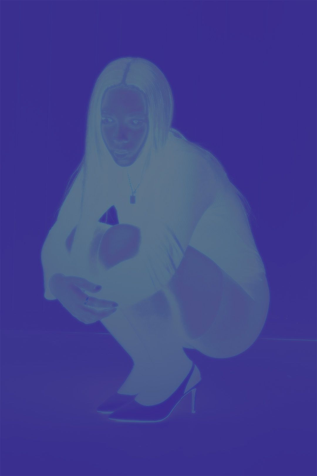 A person crouching in a blue-tinted monochrome photo, wearing a hoodie and high heels.