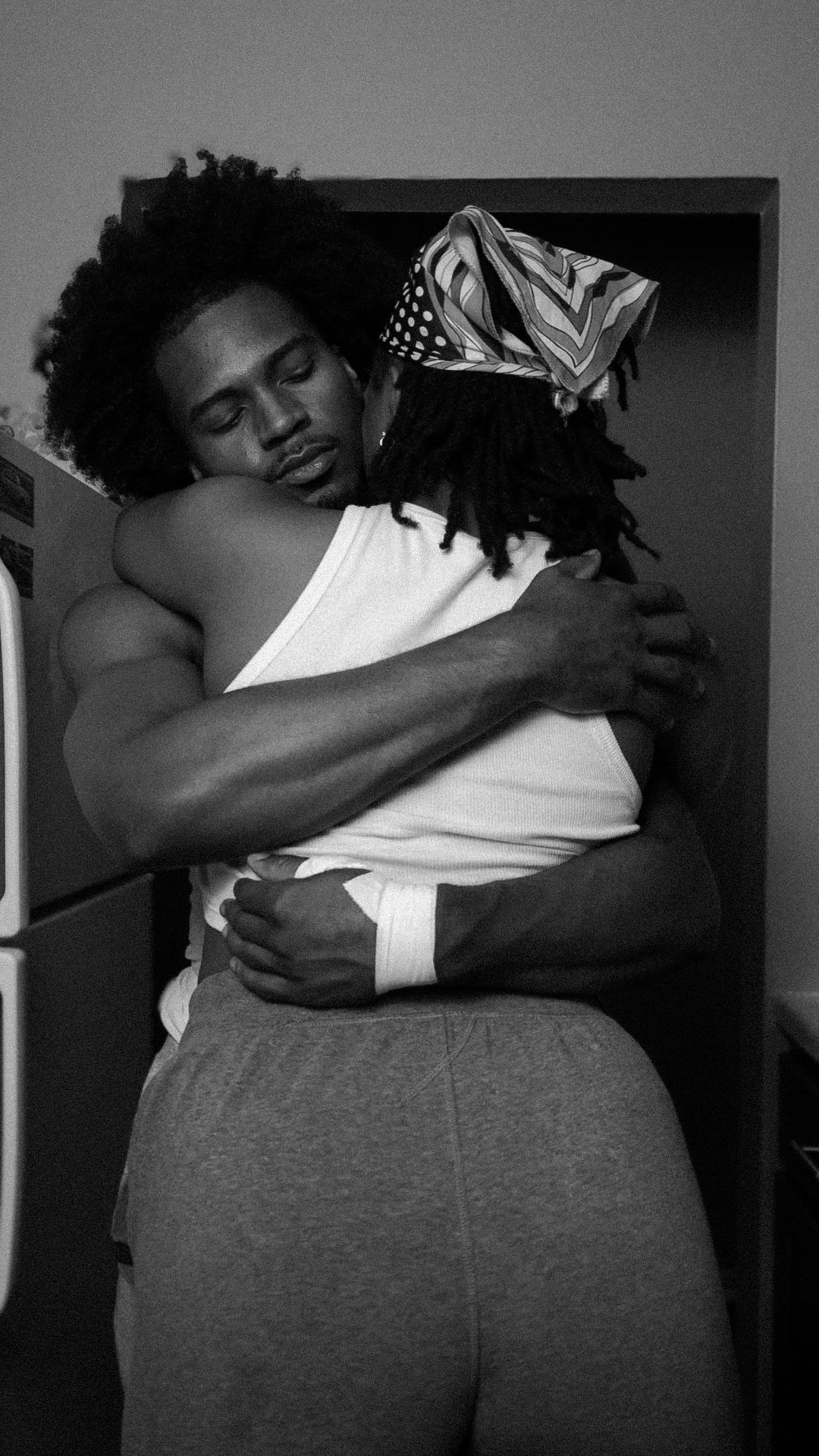 Black and white photo of a man and woman sharing a warm embrace in a doorway.