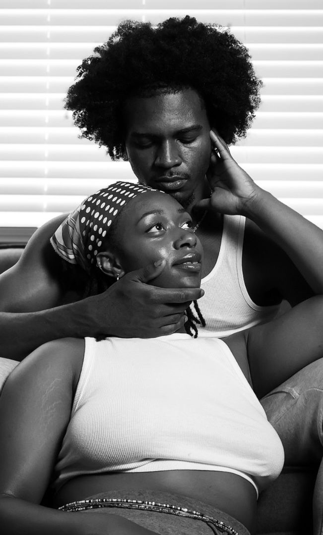 Black and white photo of a couple sitting together on a couch, man gently holding woman's face.