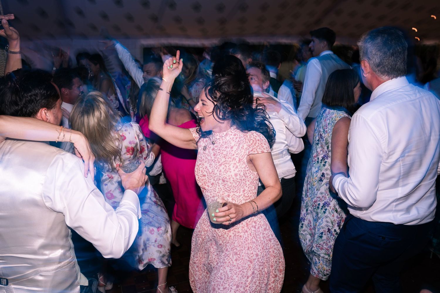 Guests dancing energetically at a wedding reception party on a crowded dance floor.