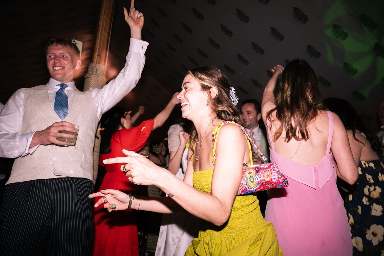 Guests in formal attire dancing and pointing at a fun wedding reception party.