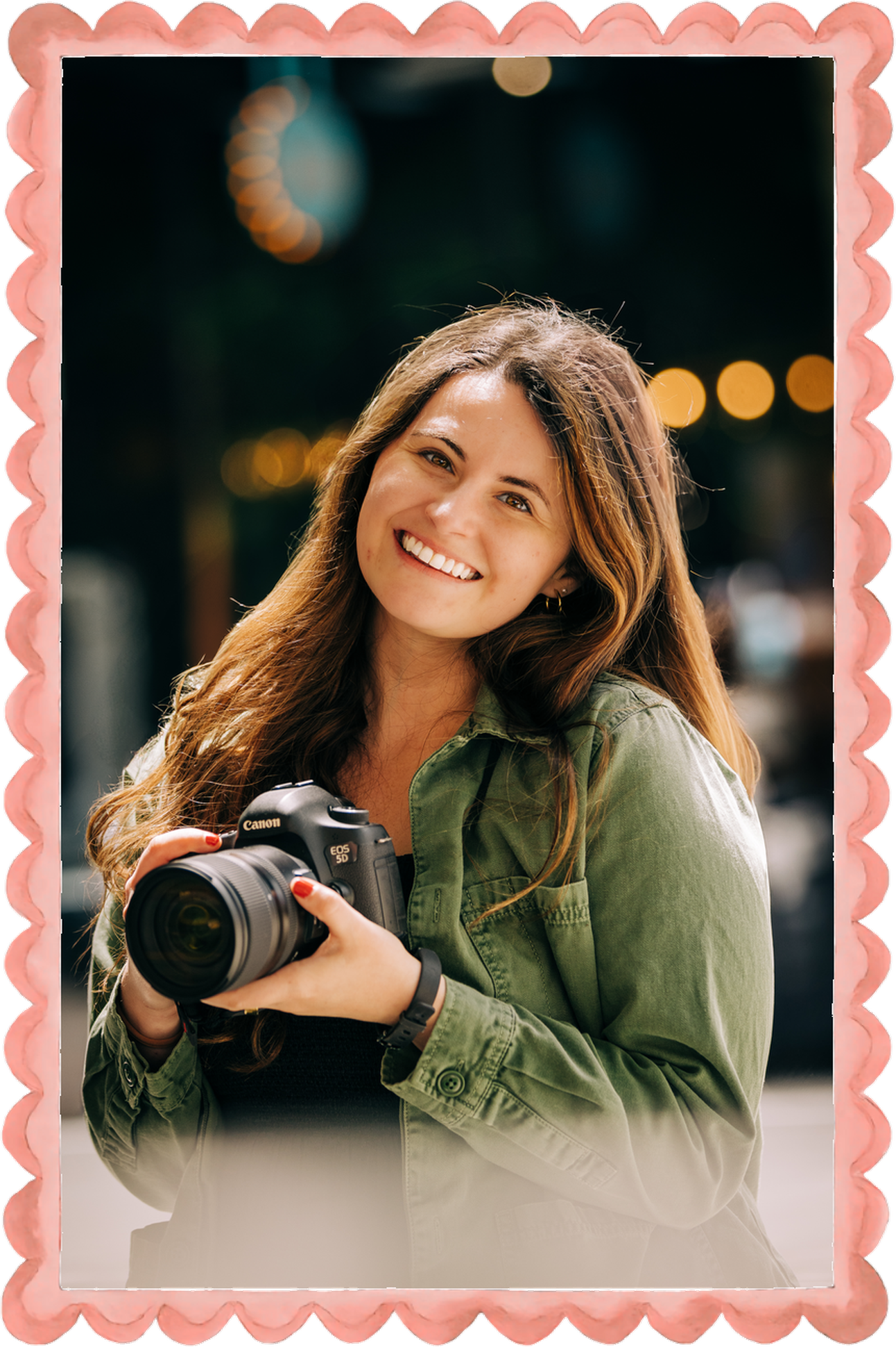 Smiling woman with long brown hair holding a Canon DSLR camera, wearing a green jacket with bokeh lights in background. Lexi Laginess Photo