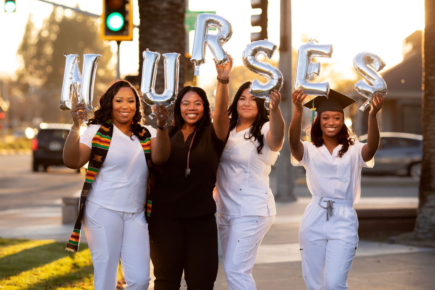 Group of four college graduates celebrating, featuring balloon letters spelling 