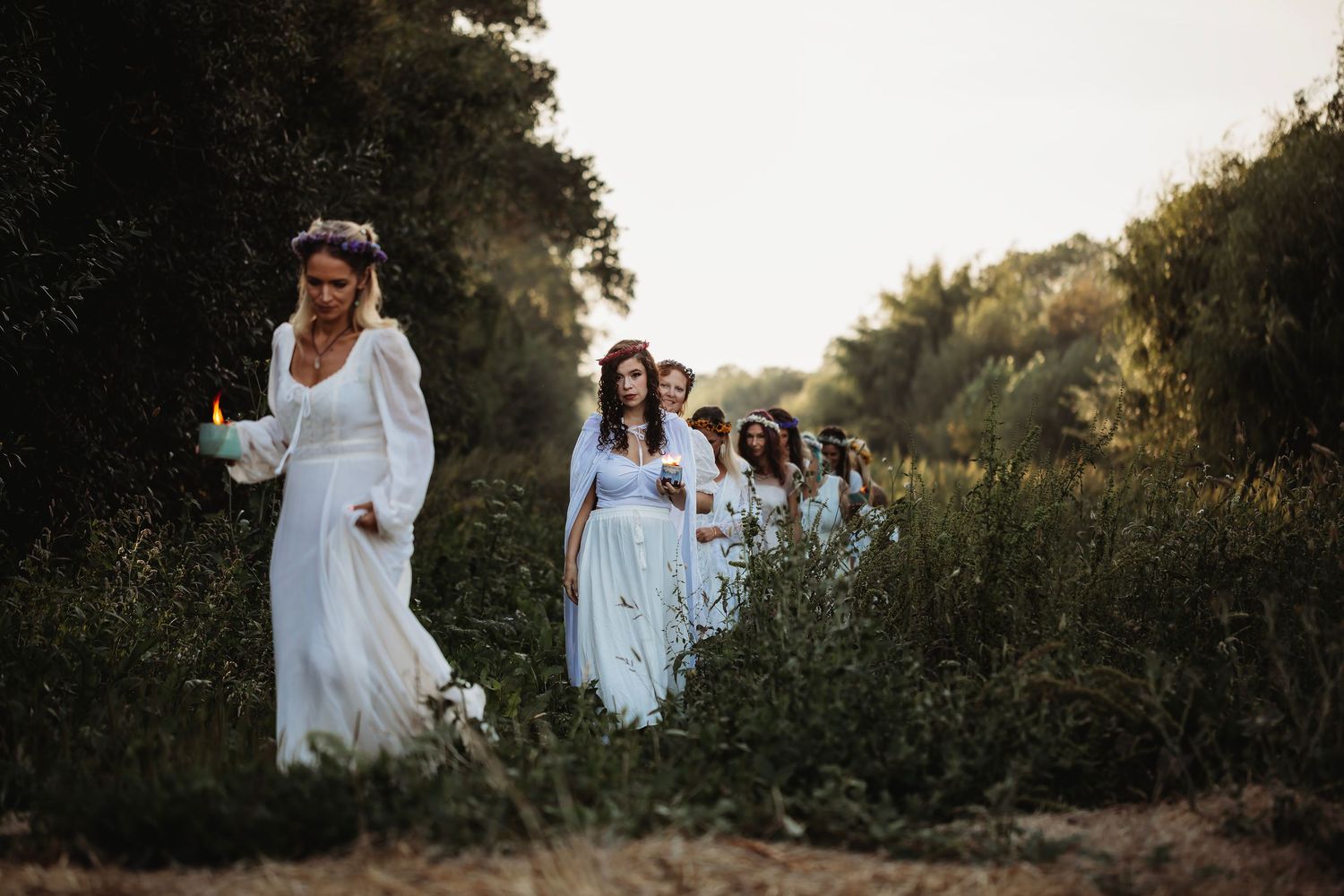 Women in flowing white dresses, walking through a meadow in a whimsical fine art portrait, inspired by nature, sisterhood, and storytelling.
