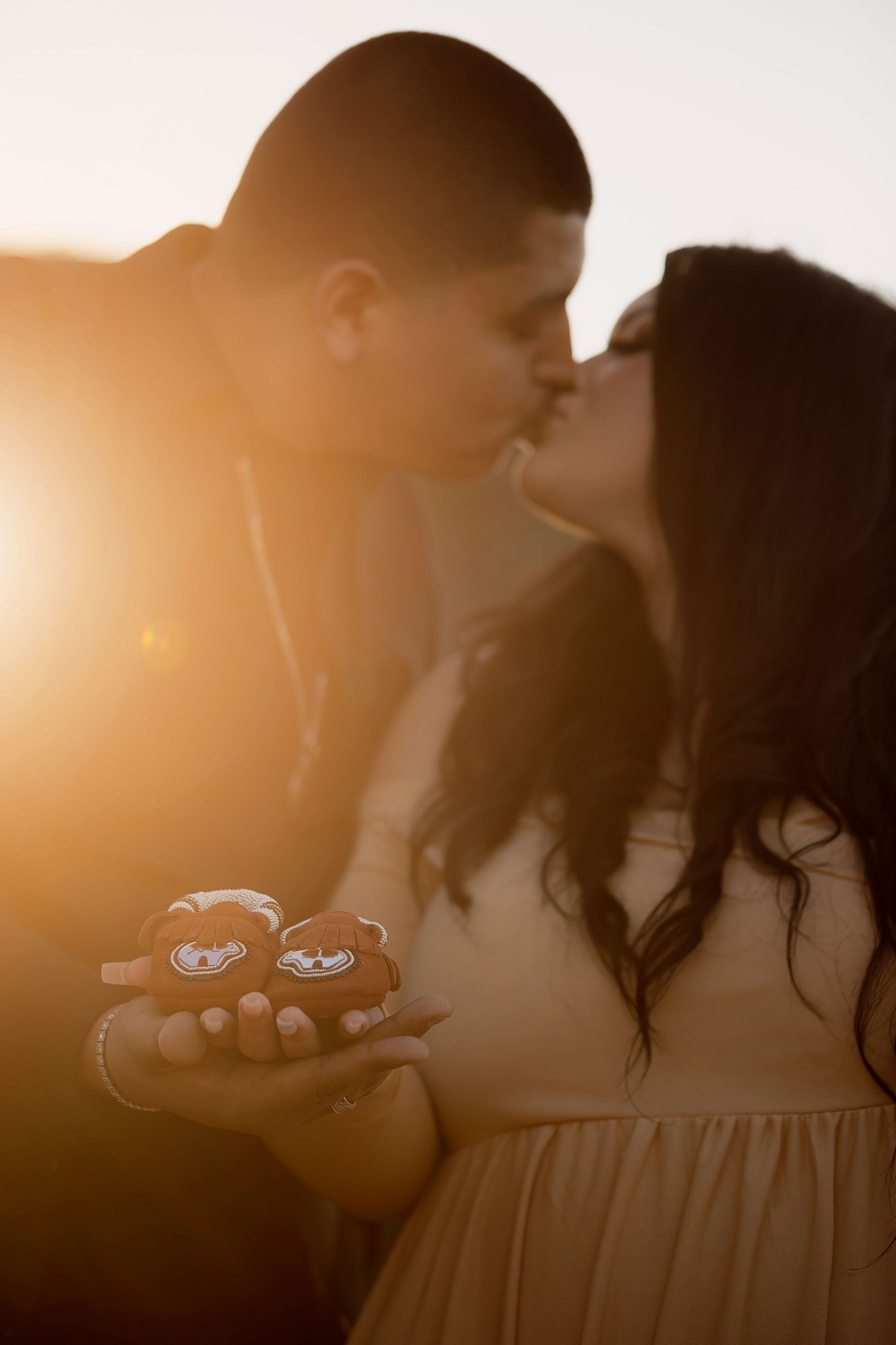 Romantic maternity portrait of an expecting couple embracing and warm sunset light by the ocean