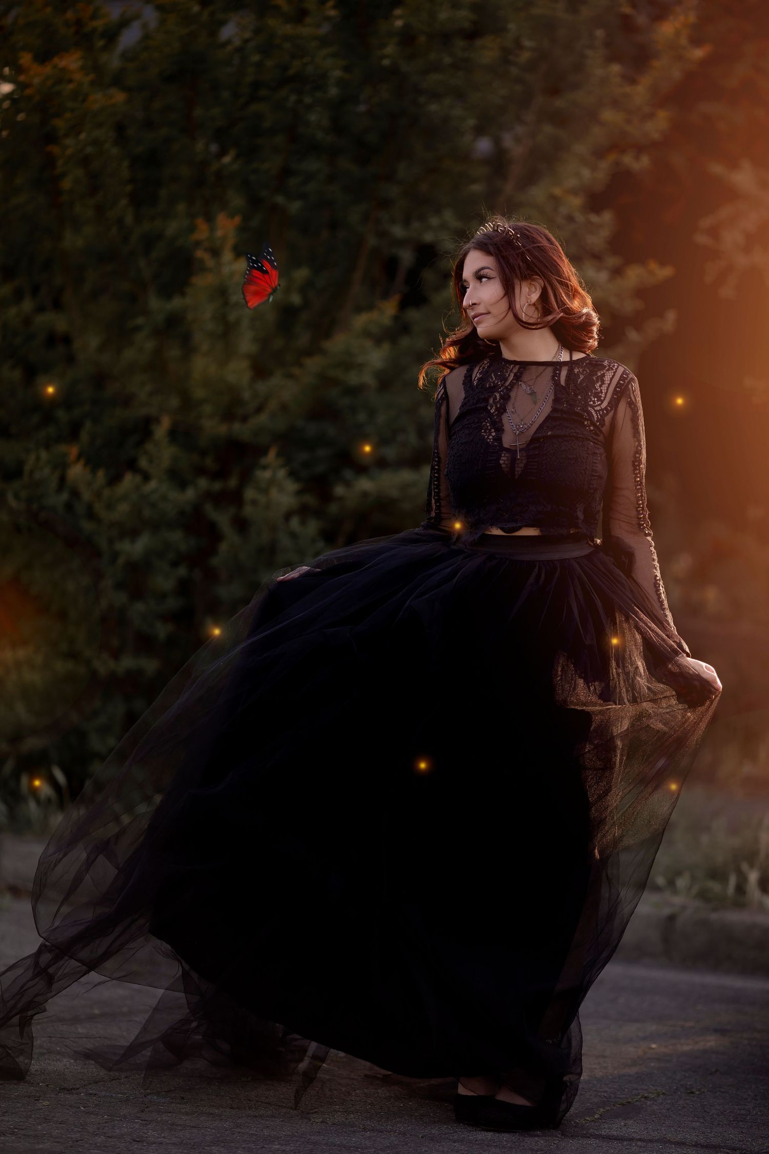 Storytelling portrait of a high school senior in a flowing black dress, surrounded by warm light and whimsical atmosphere.