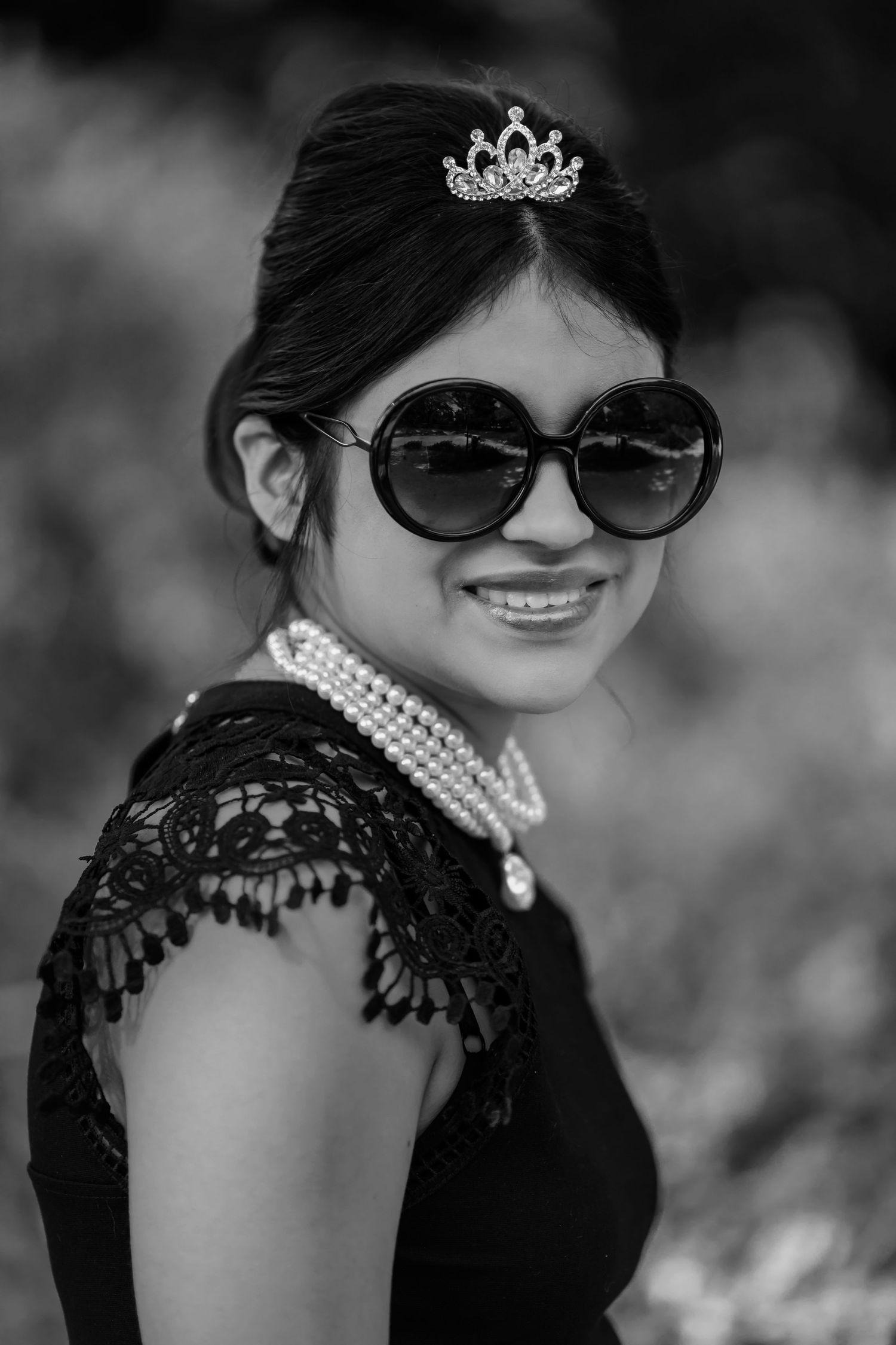 Fine art black and white portrait session featuring a young woman in a tiara and sunglasses