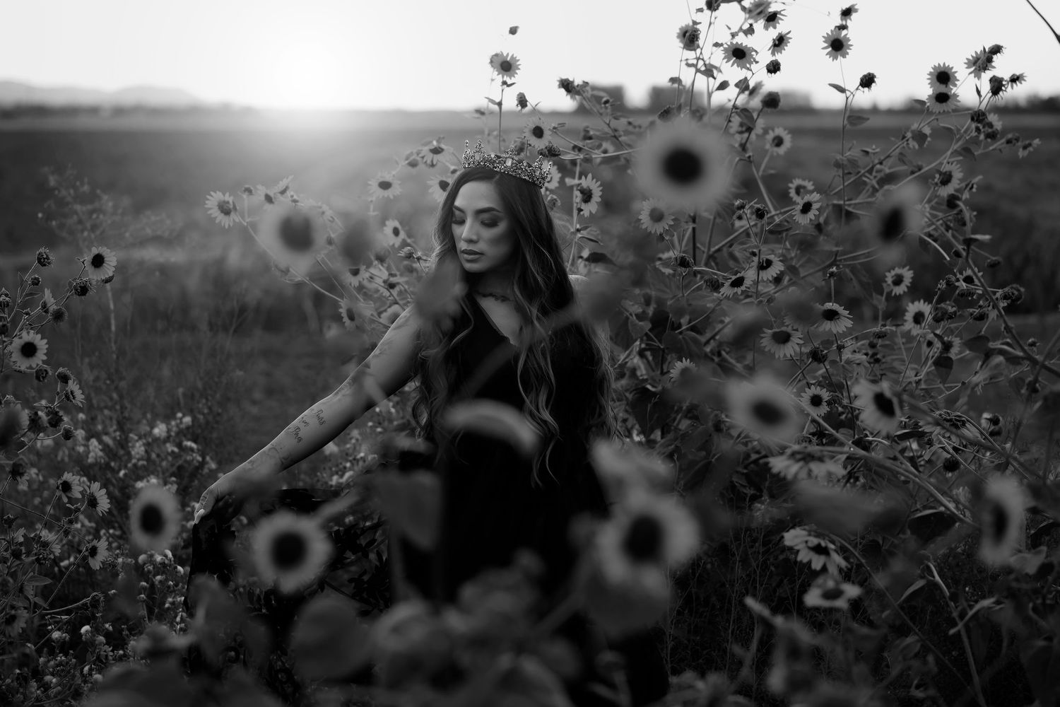 Woman surrounded by sunflowers in a black and white fine art portrait with a dreamy timeless atmosphere.