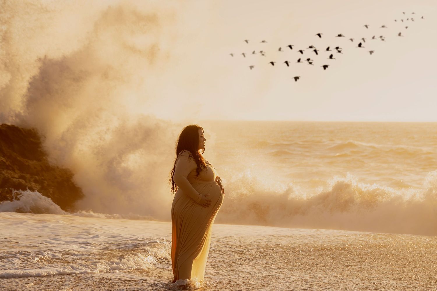 Artistic maternity portrait photographed along the Northern California coastline with dramatic ocean waves and golden sunset light