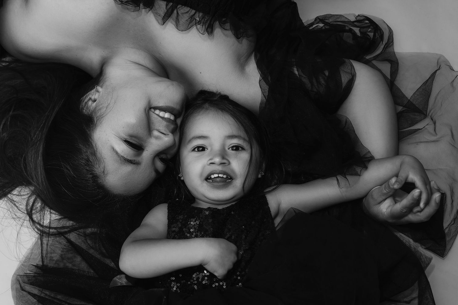 Mother and daughter sharing a tender embrace in a fine art motherhood portrait with soft, timeless styling.