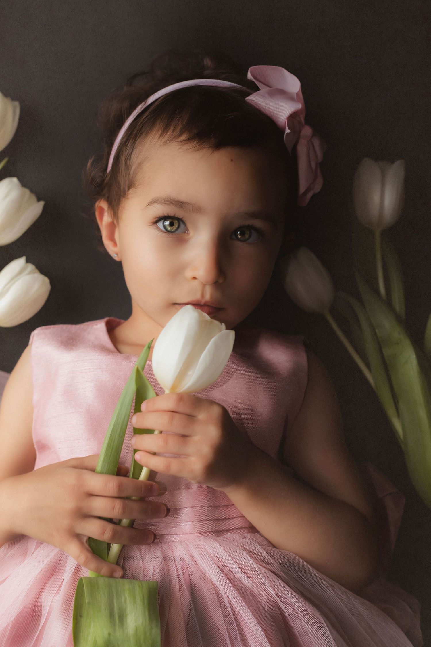 Young girl in a pink dress, holding a white tulip in a whimsical fine art child portrait with soft floral style.