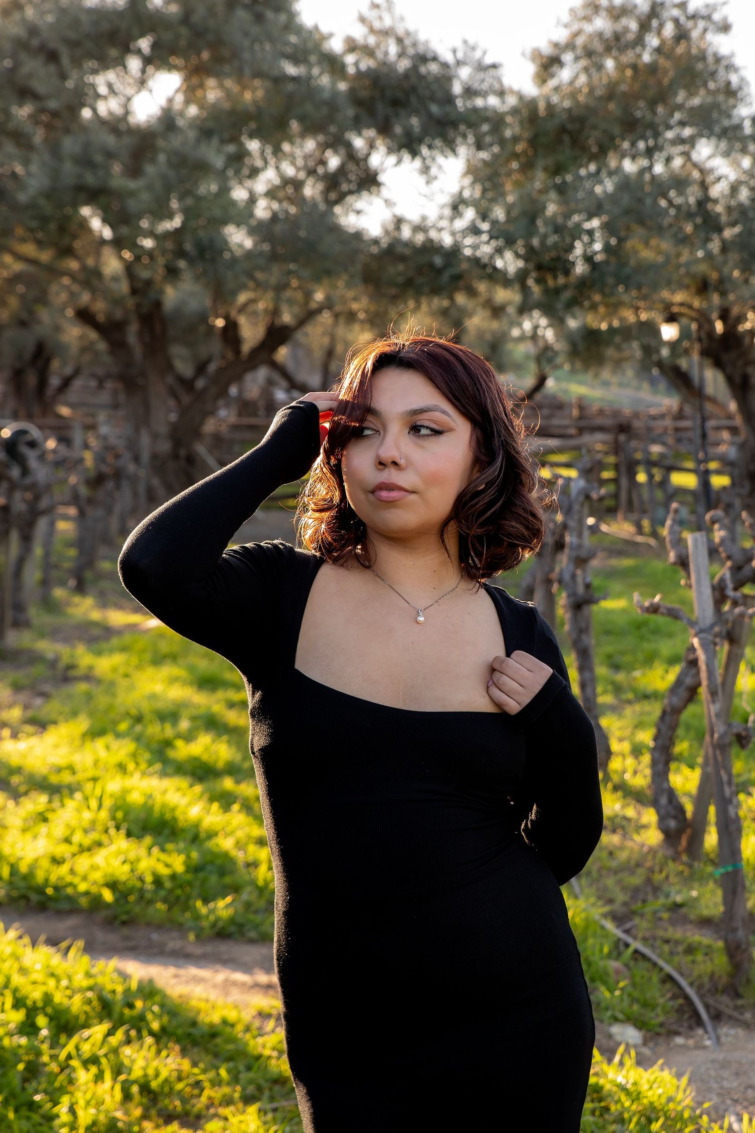 Outdoor portrait session featuring a young woman in a black dress photographed in warm golden light