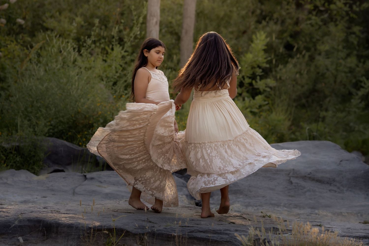 Two young girls, twirling and flowing dresses during a whimsical outdoor portrait session in Santa Rosa, California