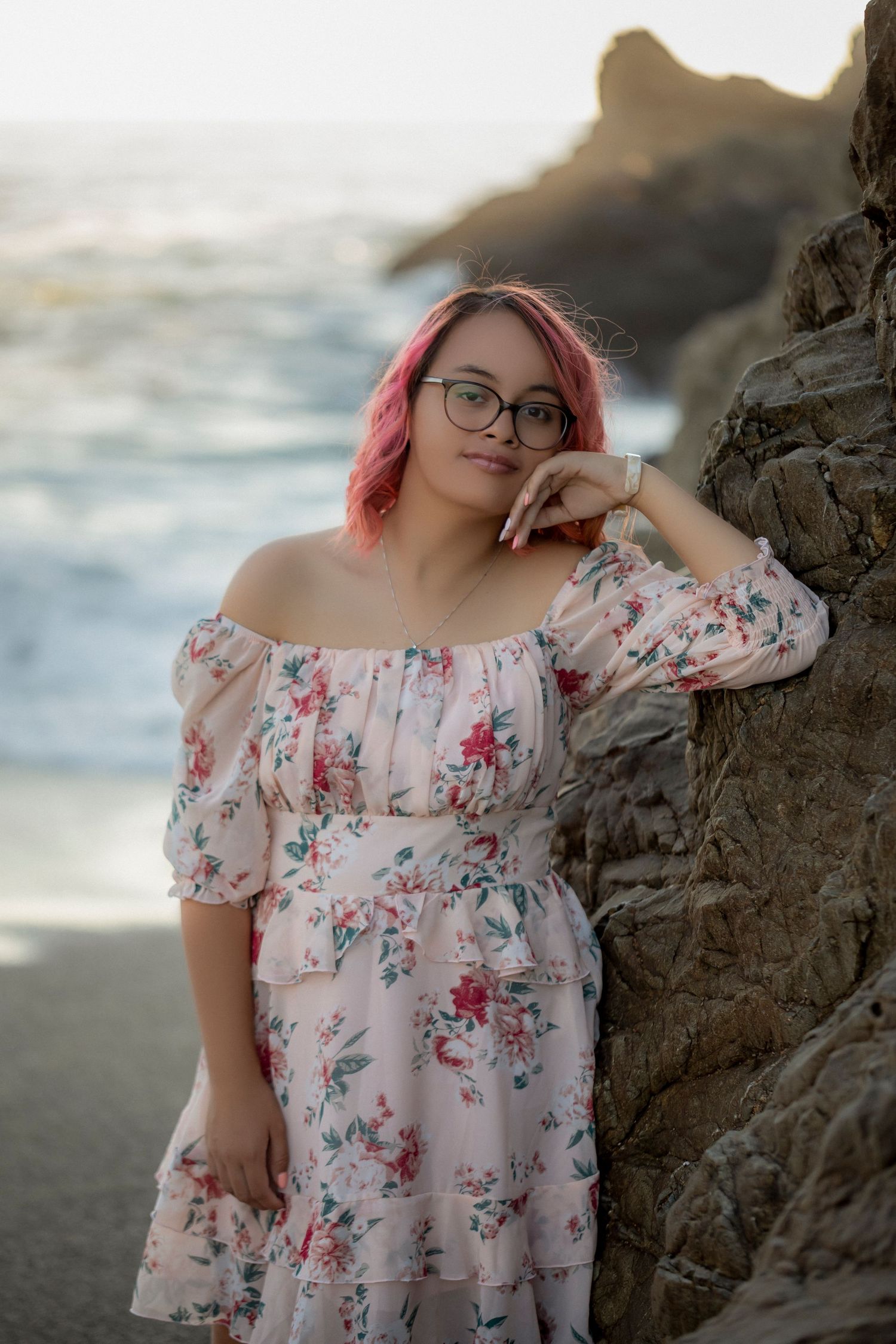 Fine art portrait of a young woman in a floral dress photographed among coastal rock formations