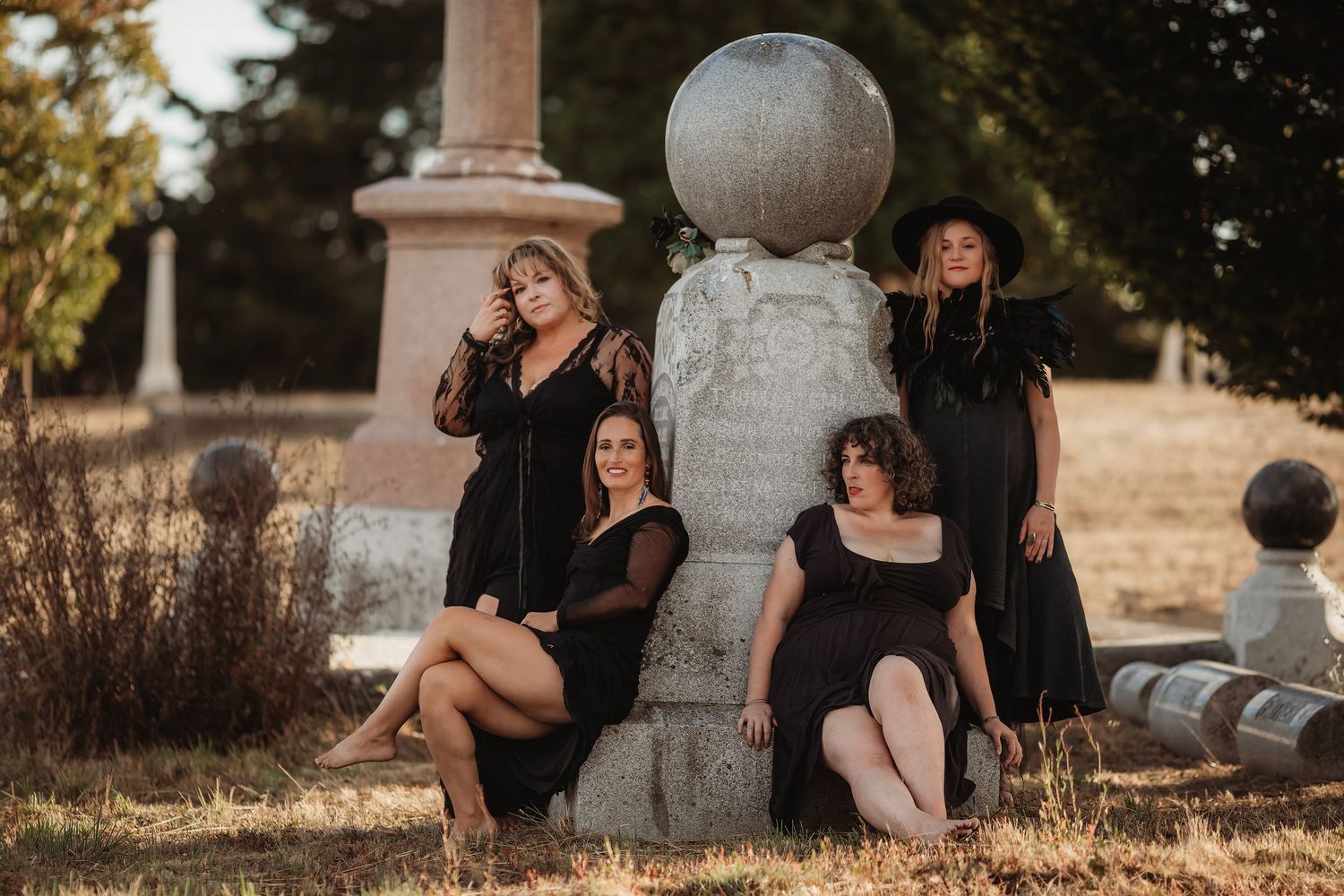Group portrait of women dressed in black around a headstone during an artistic fine art photography session for Halloween in Petaluma.