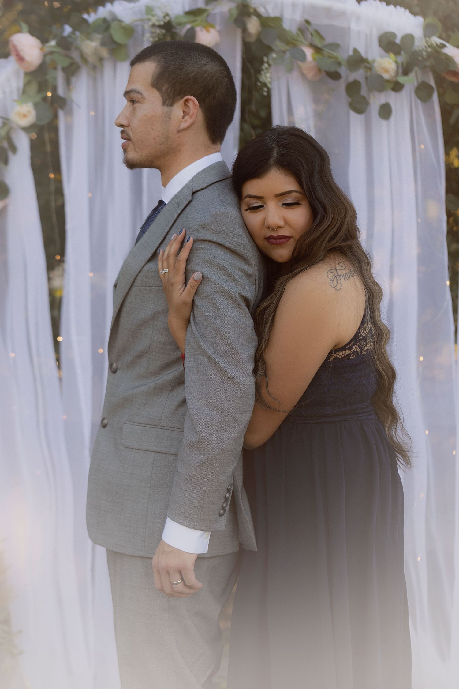 Private elopement featuring a man and woman embracing beneath a floral arch during an intimate outdoor ceremony