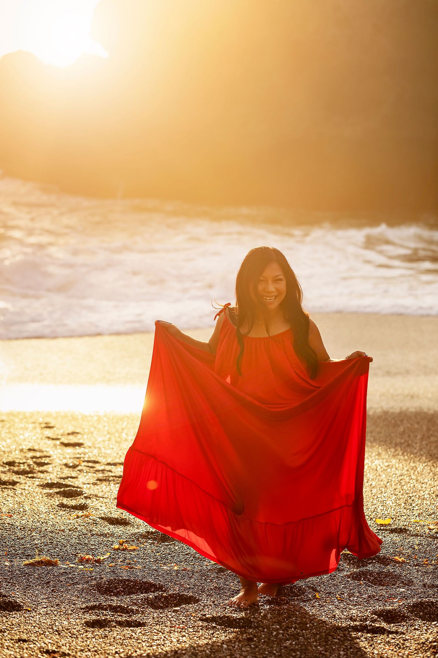 Fine art beach portrait featuring a woman in flowing red fabric at sunset along the Sonoma Coast