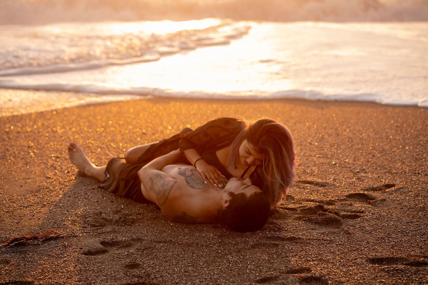 Couple embracing on a Sonoma County beach at sunset in a romantic, fine art portrait.