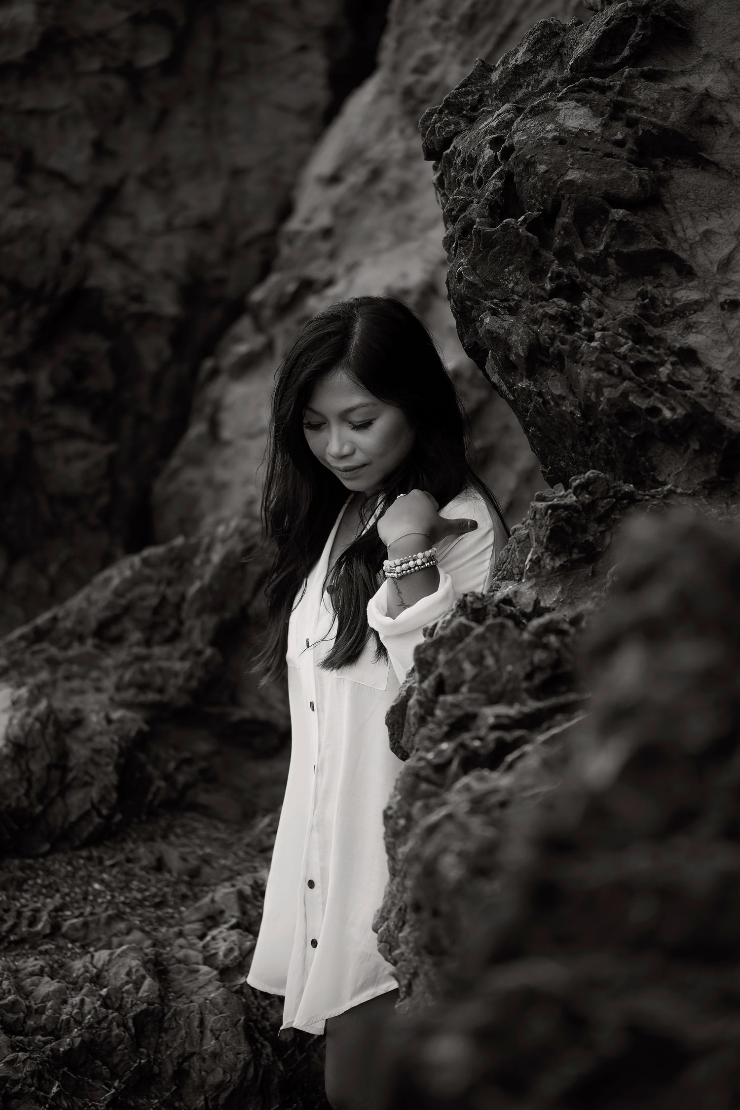 Fine art black and white portrait of a woman photographed among coastal rock formations