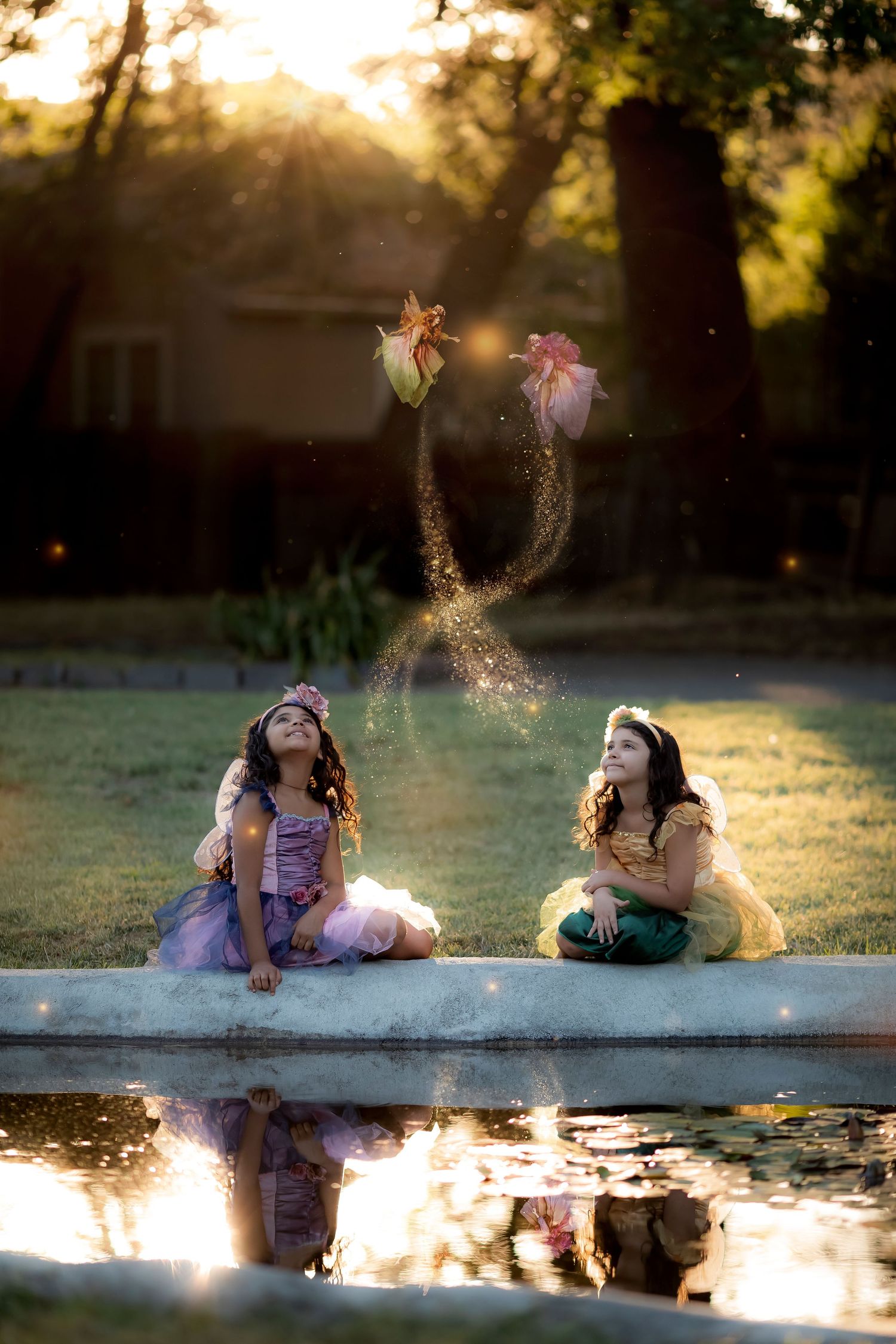 Whimsical childhood portrait featuring sisters beside a reflective pond in warm golden evening ligh