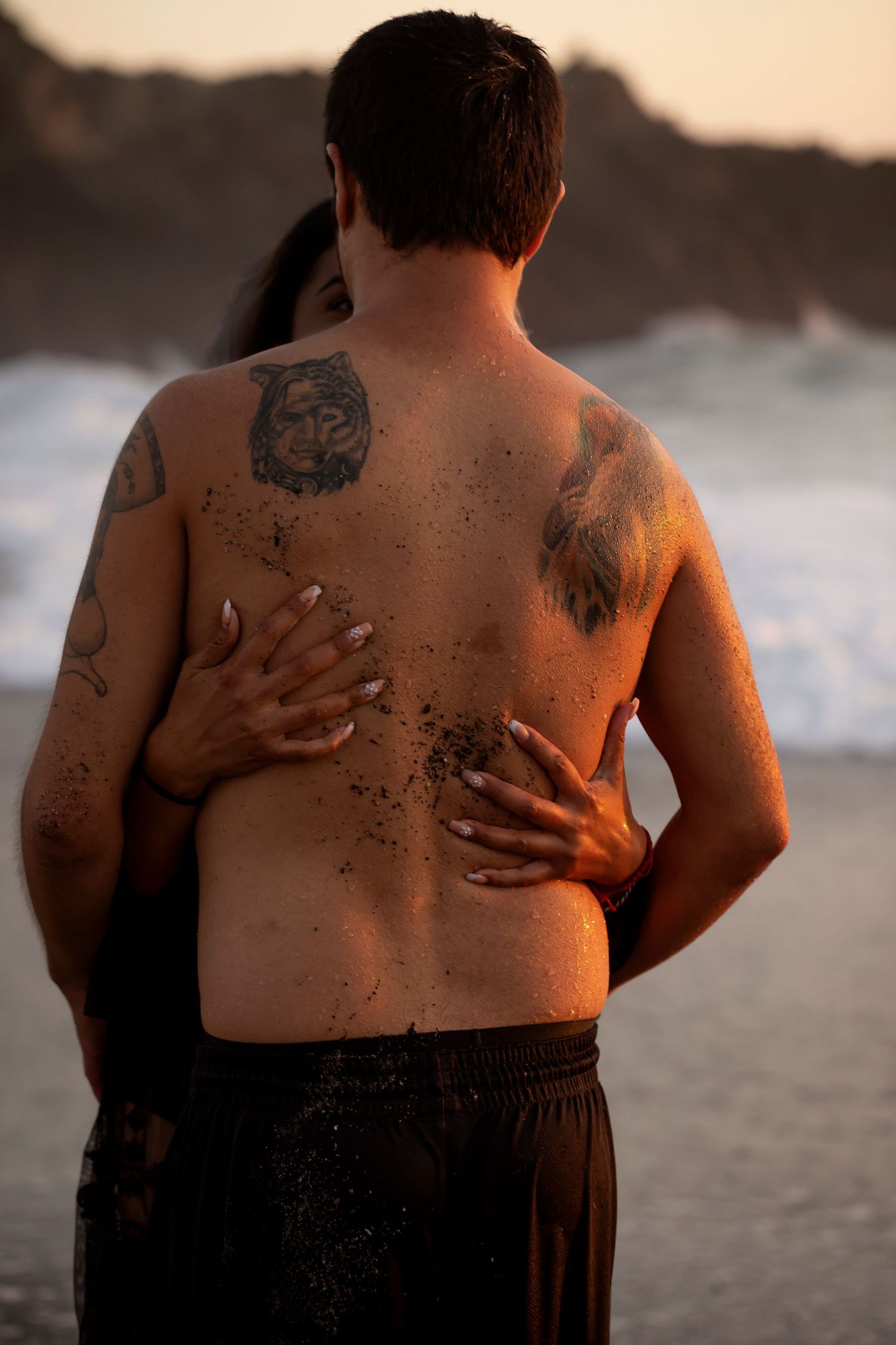 Couple embracing on a Bodega Bay beach at sunset in a romantic, fine art portrait celebrating connection and love.
