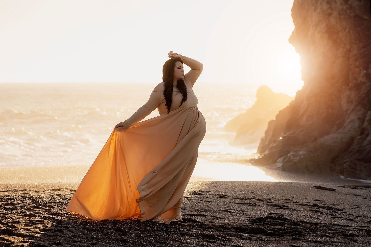 Fine art maternity portrait featuring a flowing gown photograph on a coastal beach sunset