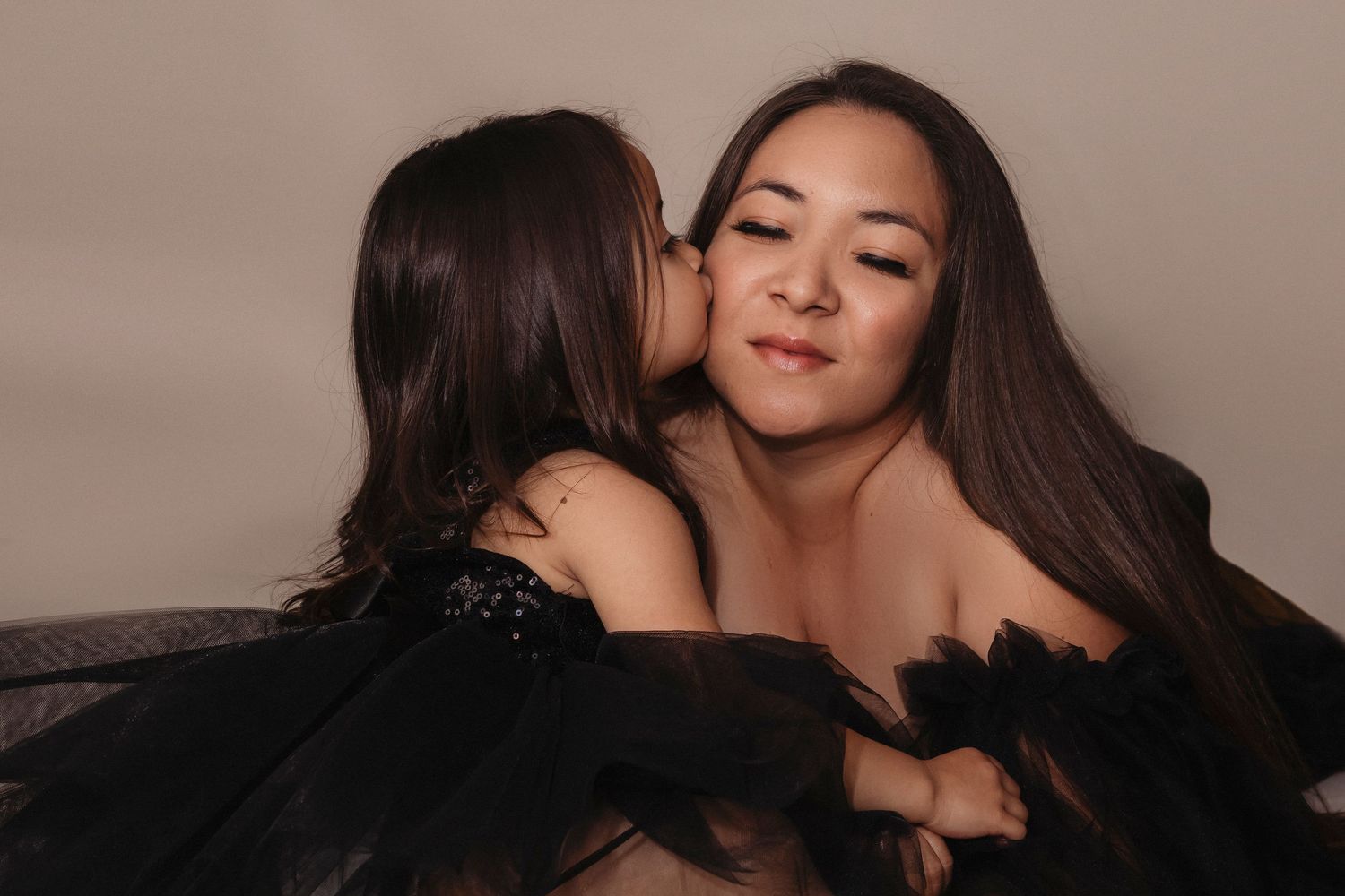 Daughter kissing her mother during a joyful family portrait filled with love and connection