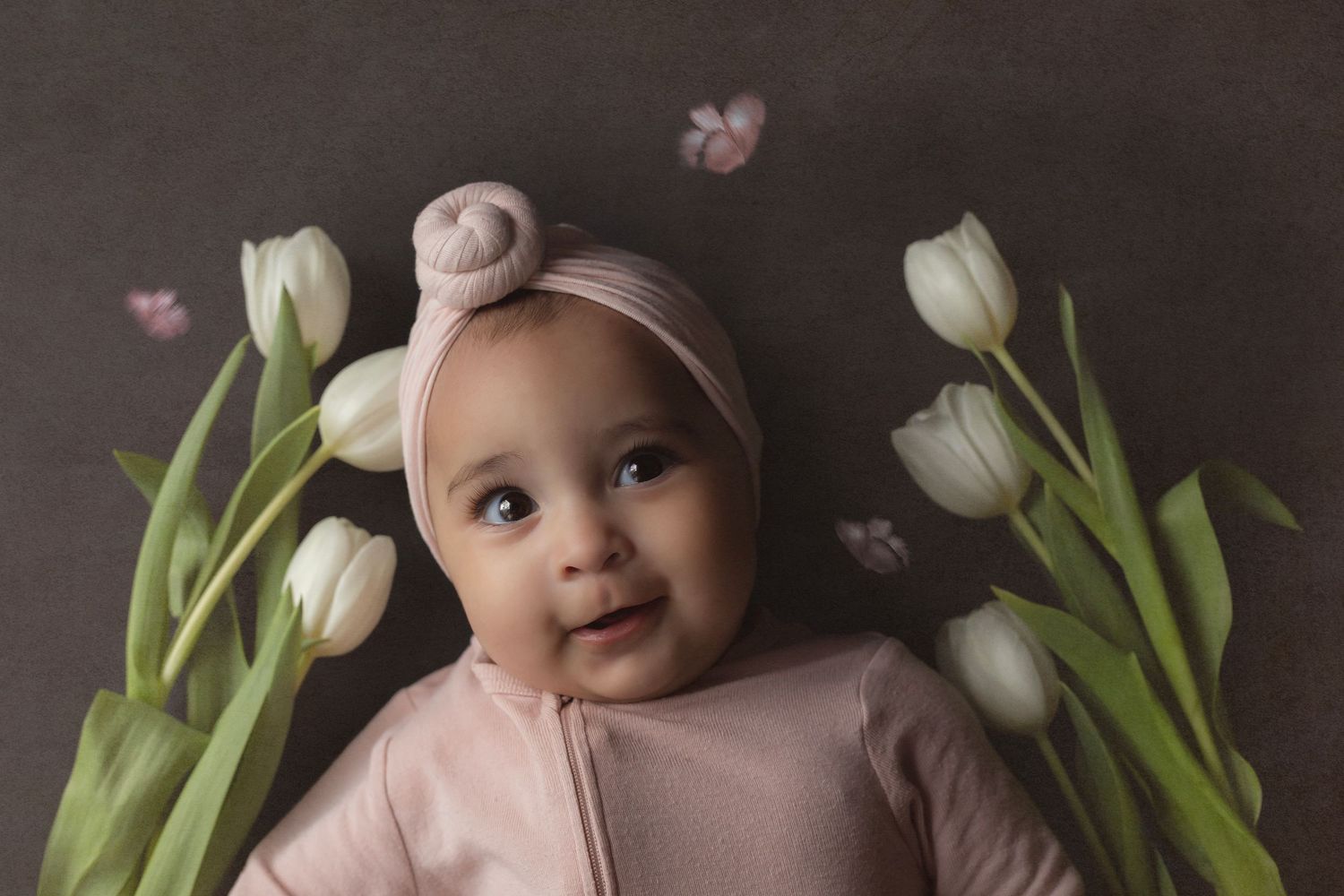 Baby girl, surrounded by white tulips in a whimsical floral portrait with pastel tones and fine art styling.