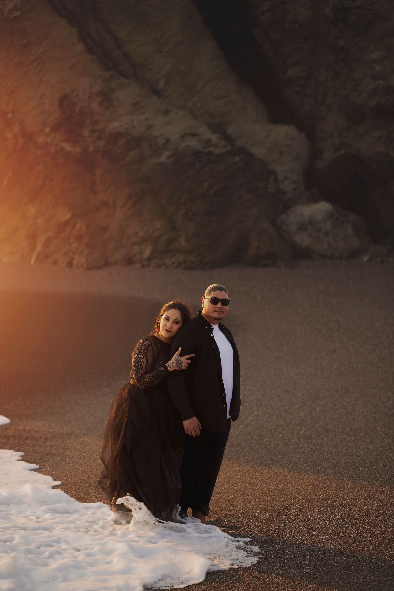 Couple standing together beneath coastal cliffs in Bodega Bay during a romantic, fine art portrait session.