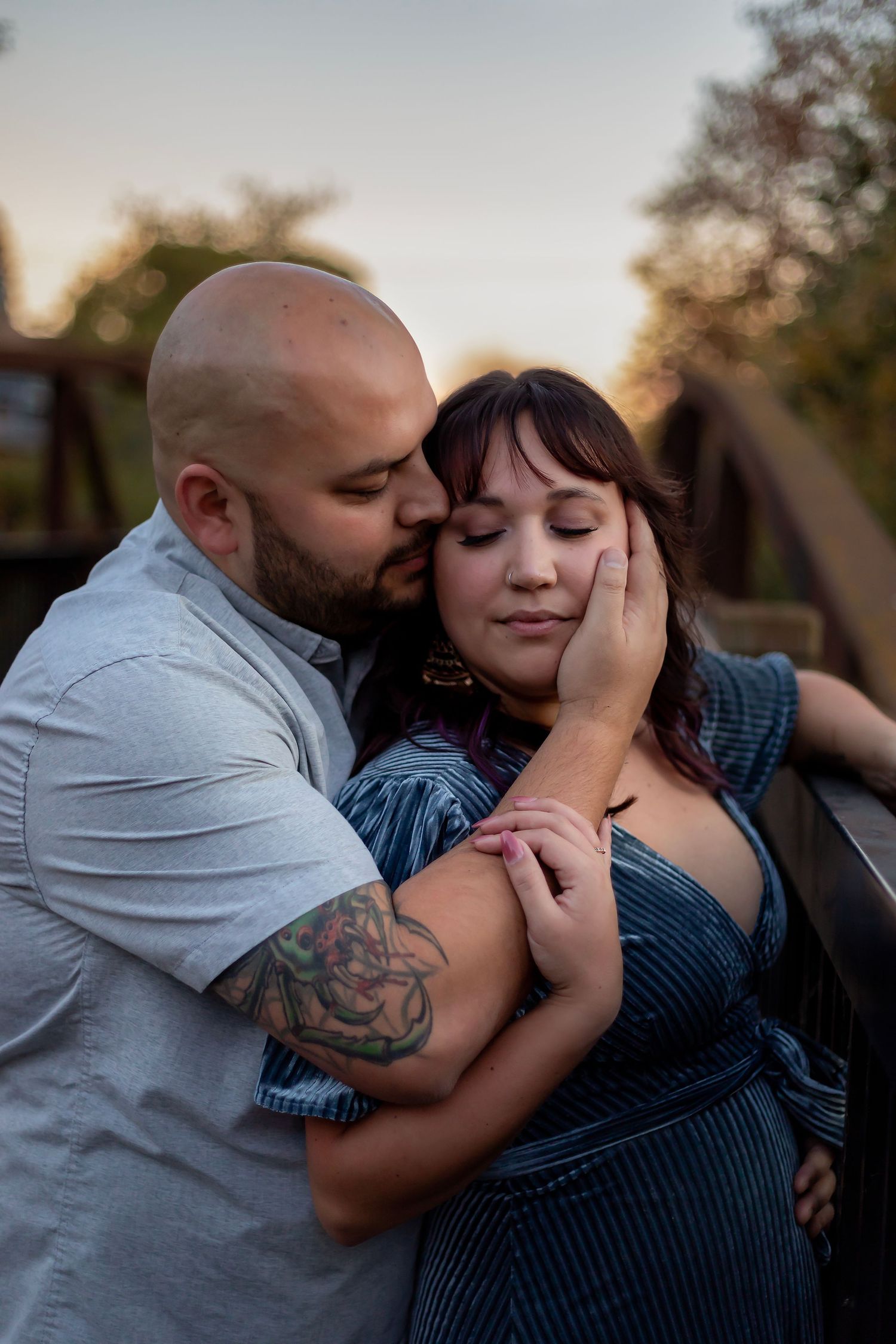 Romantic couples engagement portrait, featuring an embracing couple photographed outdoors at sunset