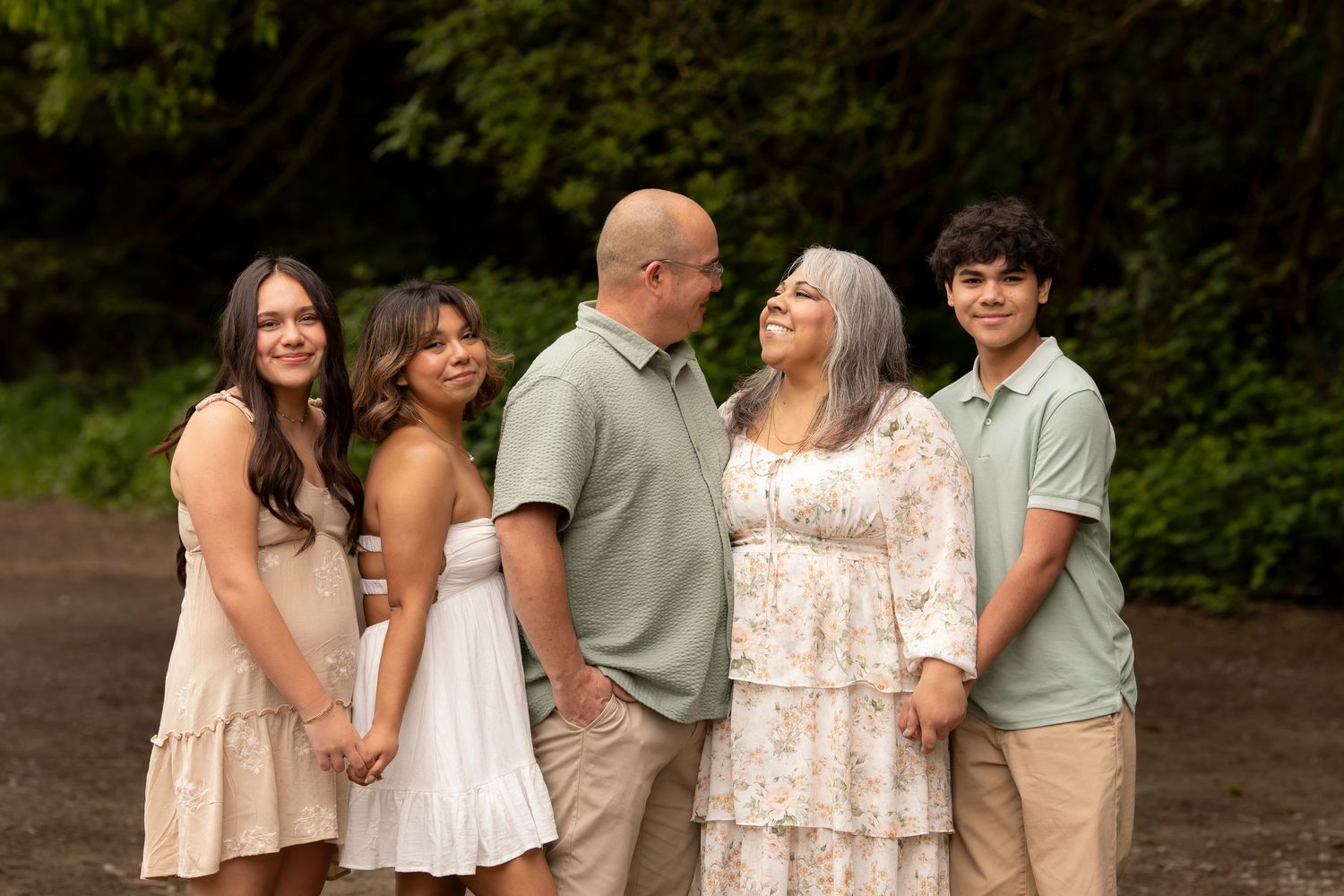 Outdoor family portrait session featuring parents and their children, sharing a candid moment together in natural light