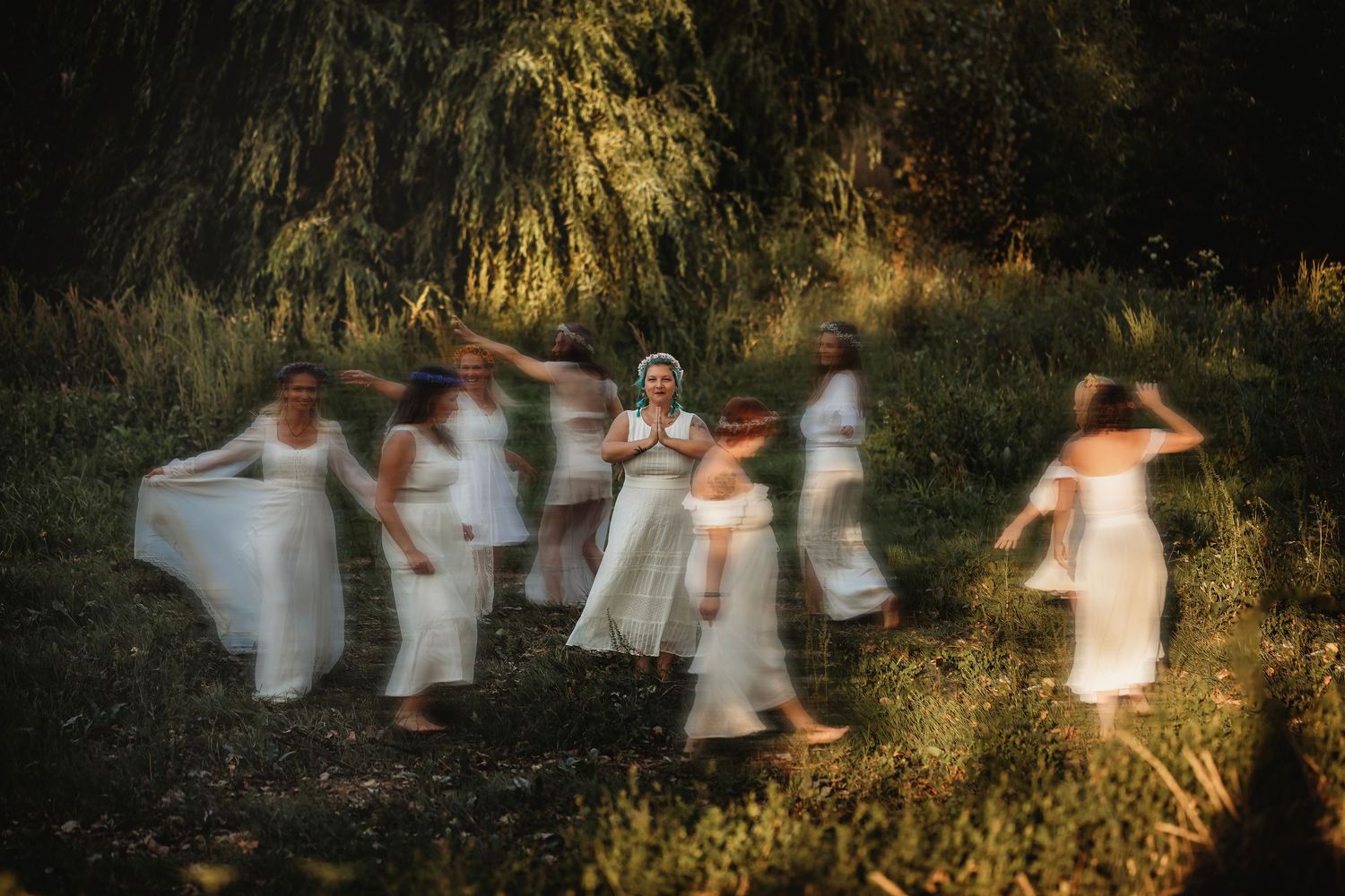 Fantasy inspired group portrait of women in flowing white dresses, dancing beneath golden sunlight in a Sonoma County meadow.