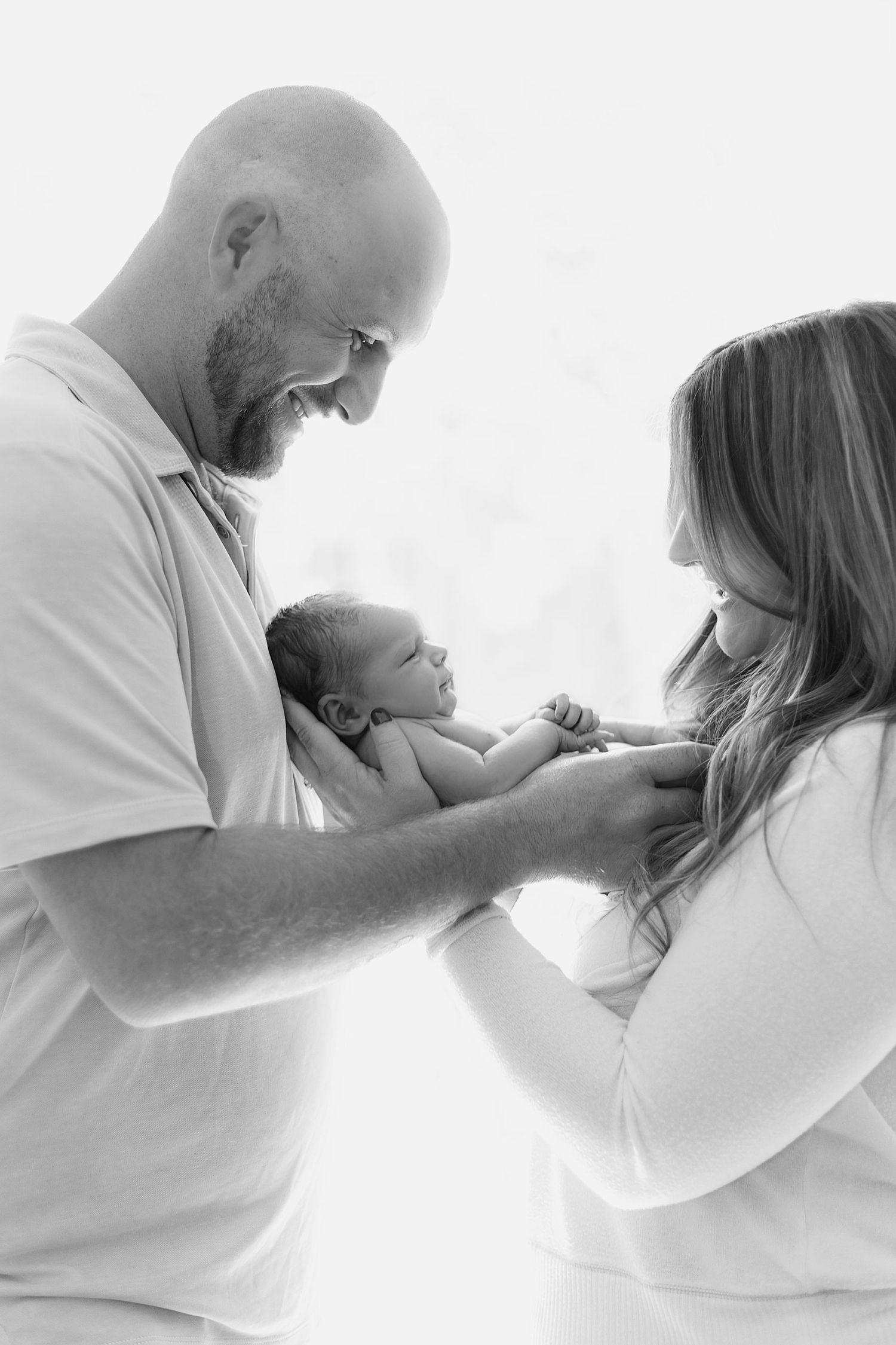 Black and white lifestyle portrait, capturing a couple sharing a quiet moment with their newborn