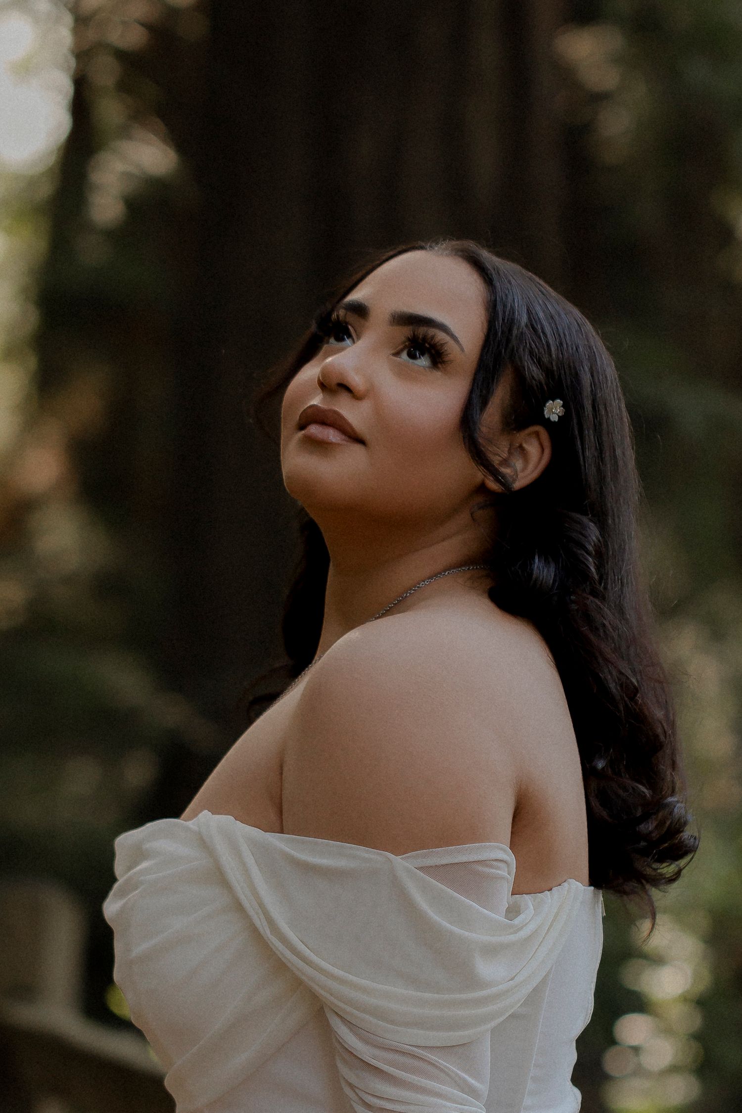 Fine art portrait of a High school senior in an off the shoulder top photographed in soft woodland light