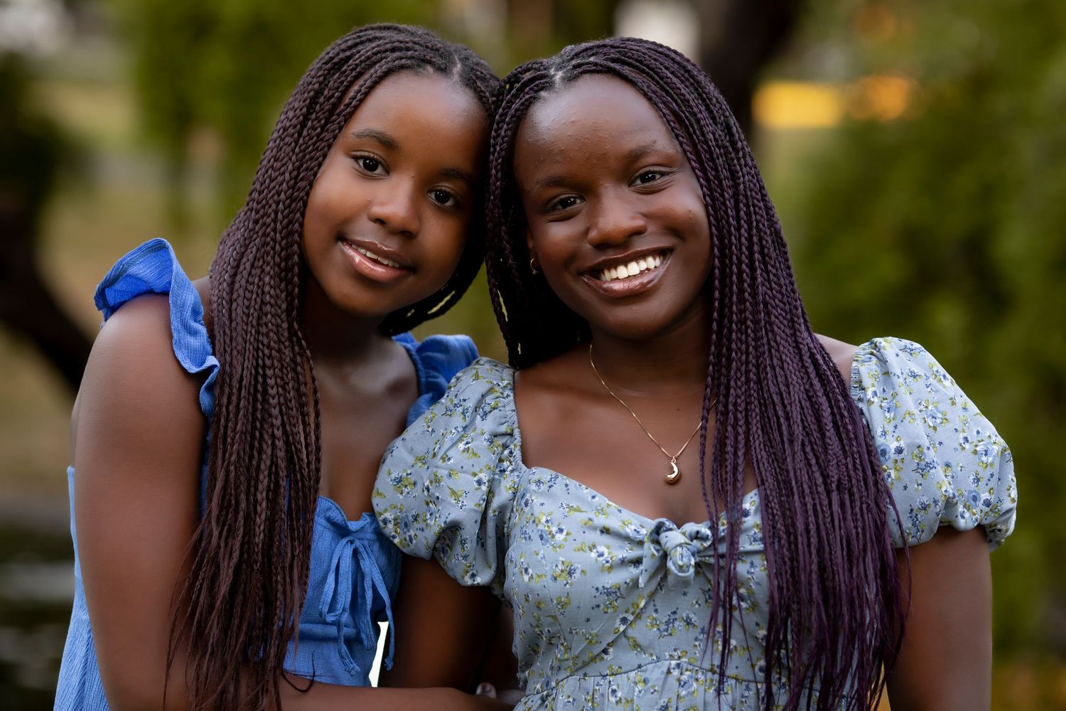 Outdoor portrait of two sisters smiling together in a garden setting during a family photography session