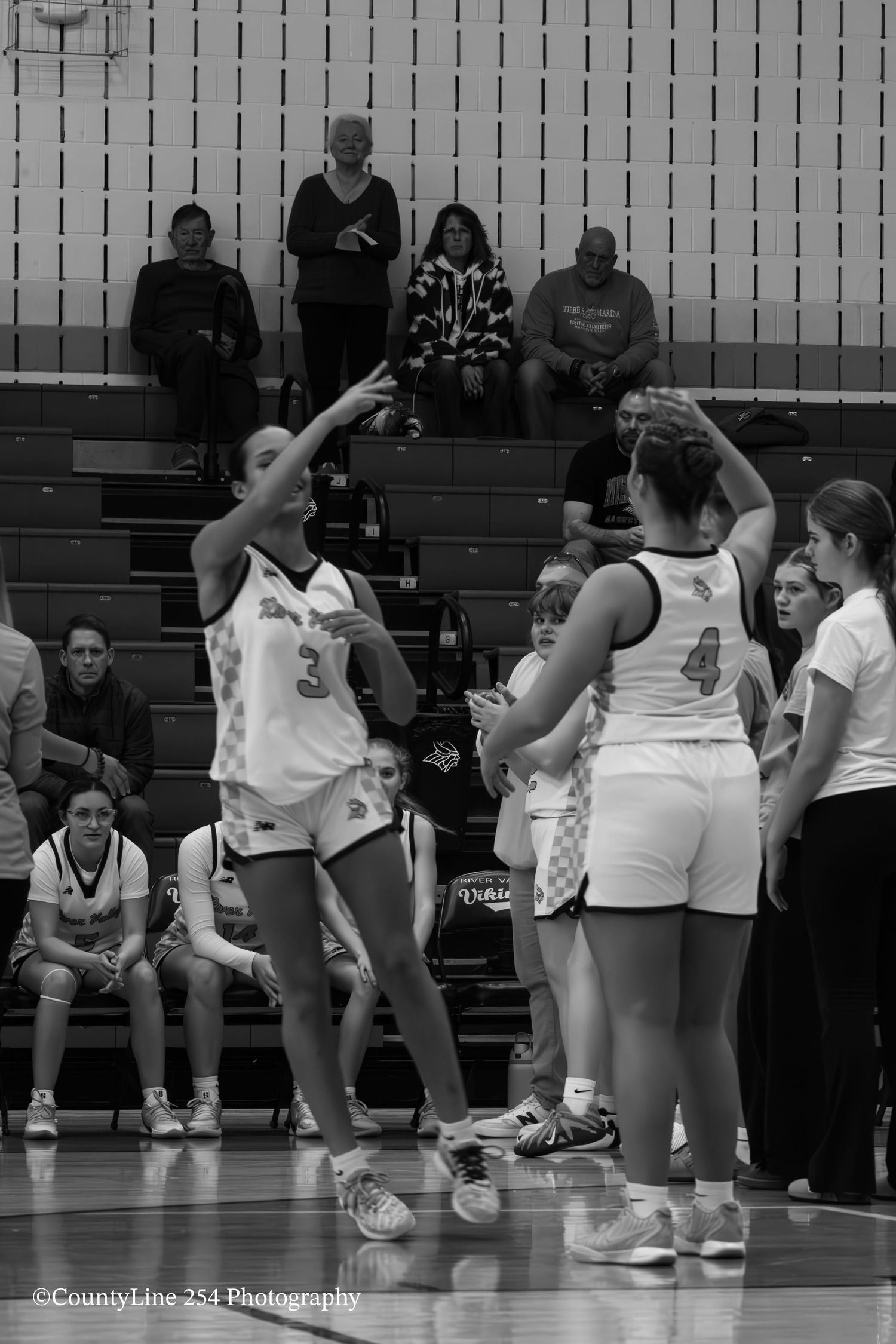 Black and white photo of female basketball players during a game, player number 3 shooting.