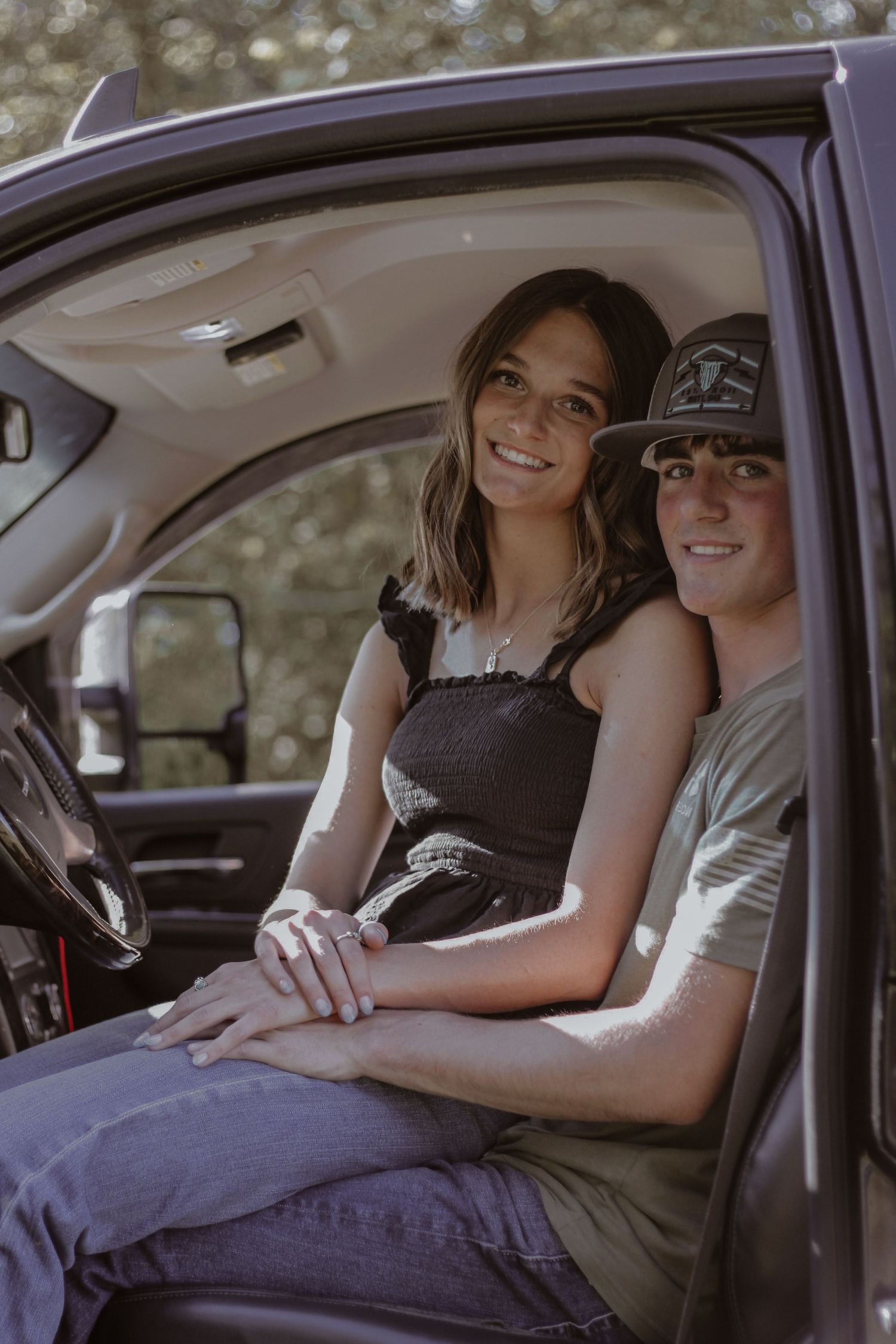 Happy couple holding hands while sitting in the front seat of a pickup truck.