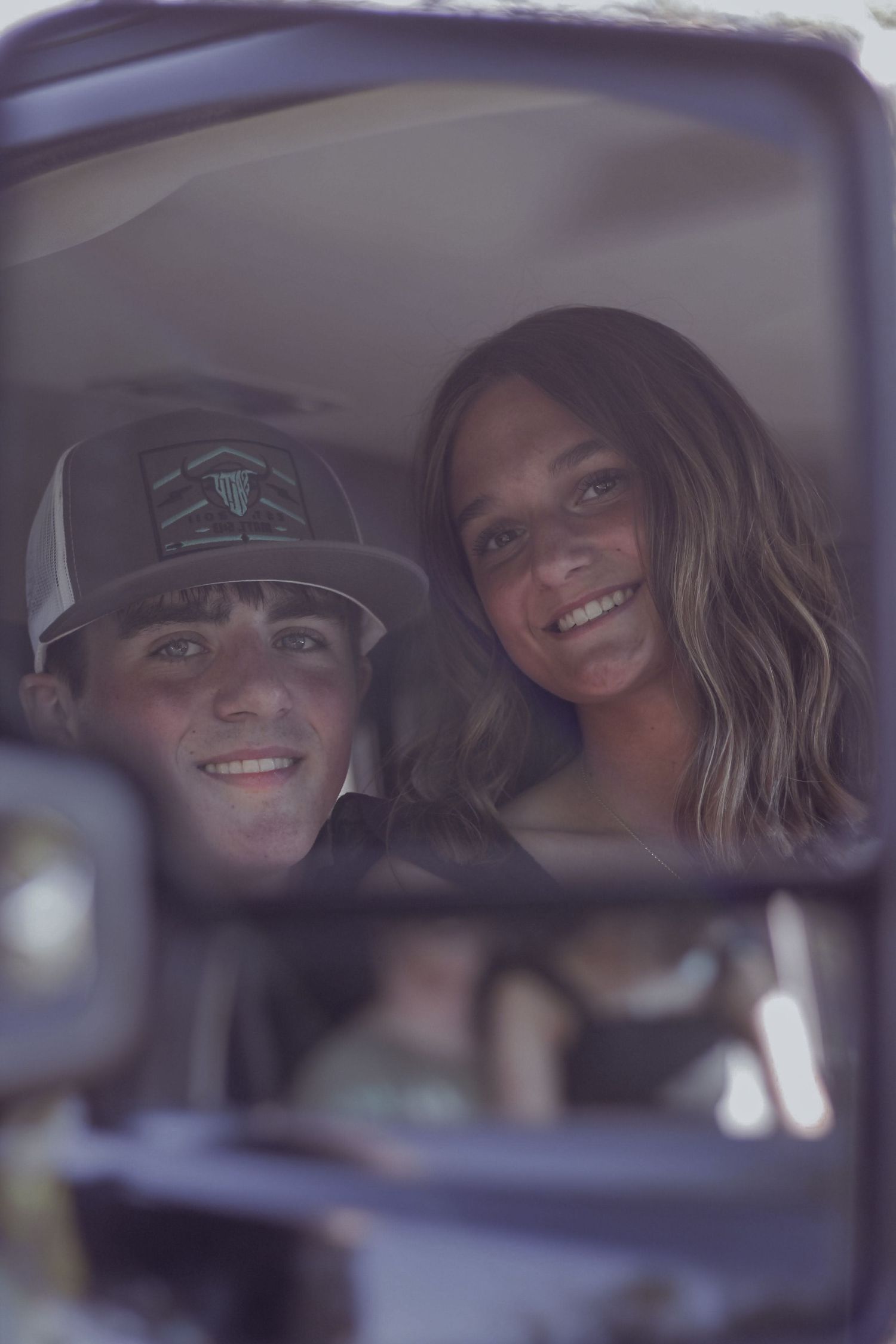 Young couple smiling through a truck window, man wearing a gray snapback cap.
