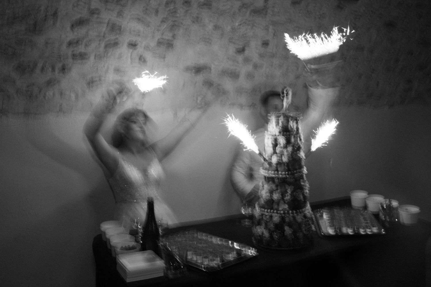Black and white photo of performers juggling fire at an indoor event near a decorated table.