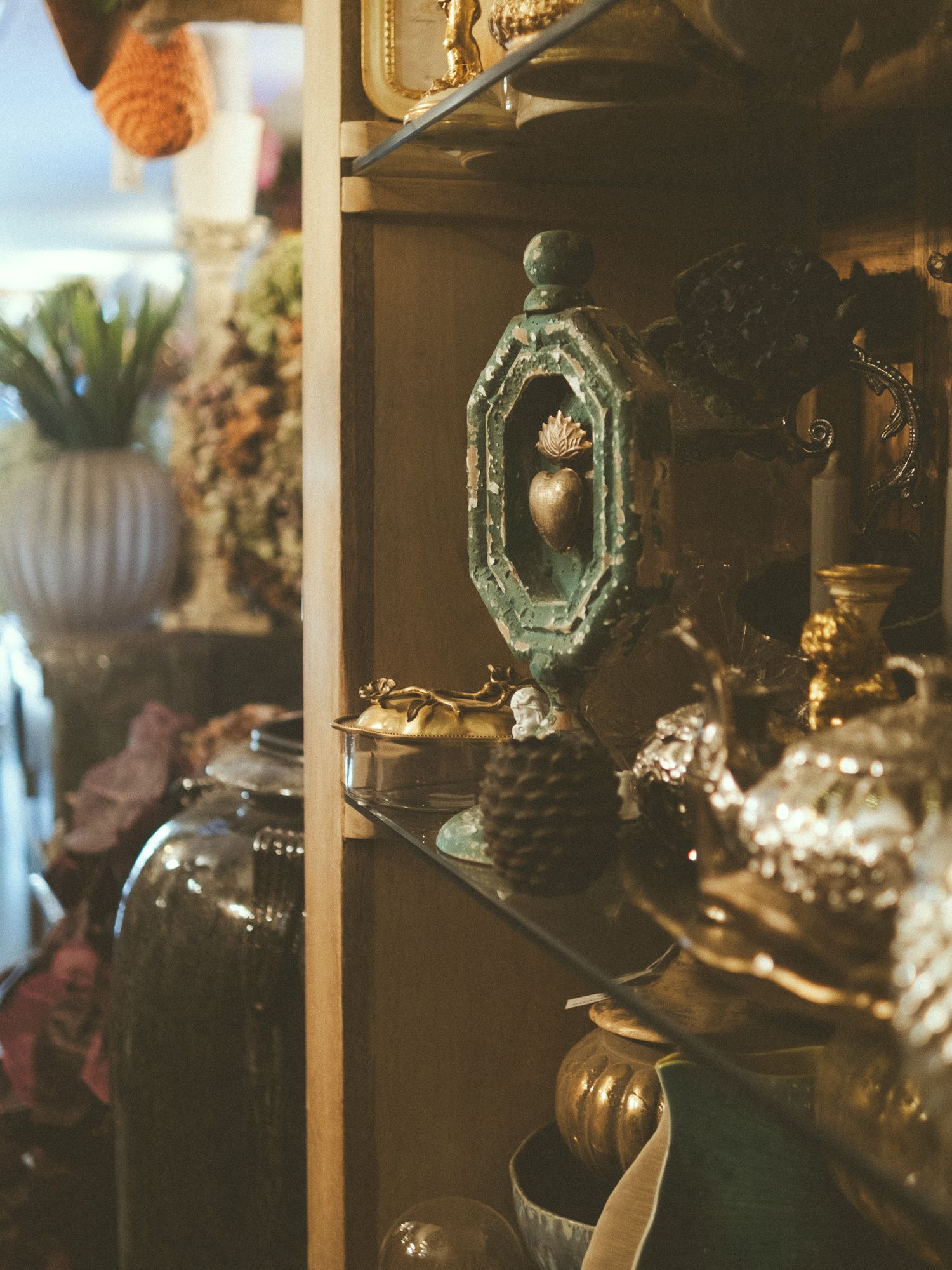 Antique shelf display with ornate brass candleholders, vintage glass jars, and decorative trinkets in a curio cabinet.