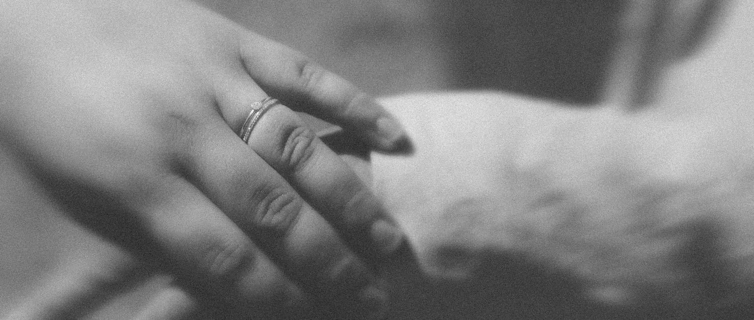 Gros plan en noir et blanc de la main d'une mariée portant une alliance.