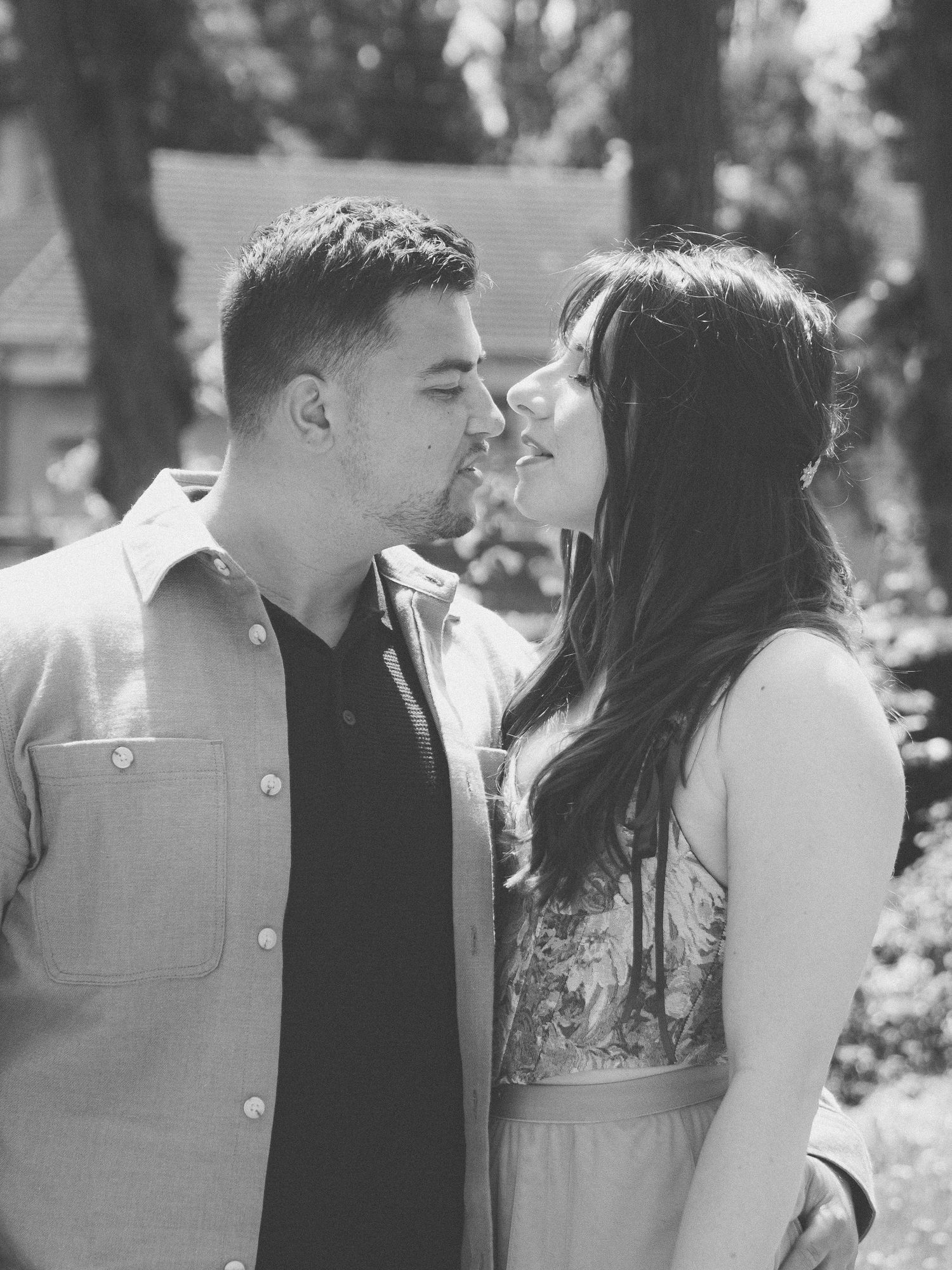 Photo romantique en noir et blanc d'un jeune couple sur le point de s'embrasser, en extérieur, dans le jardin d'un château.