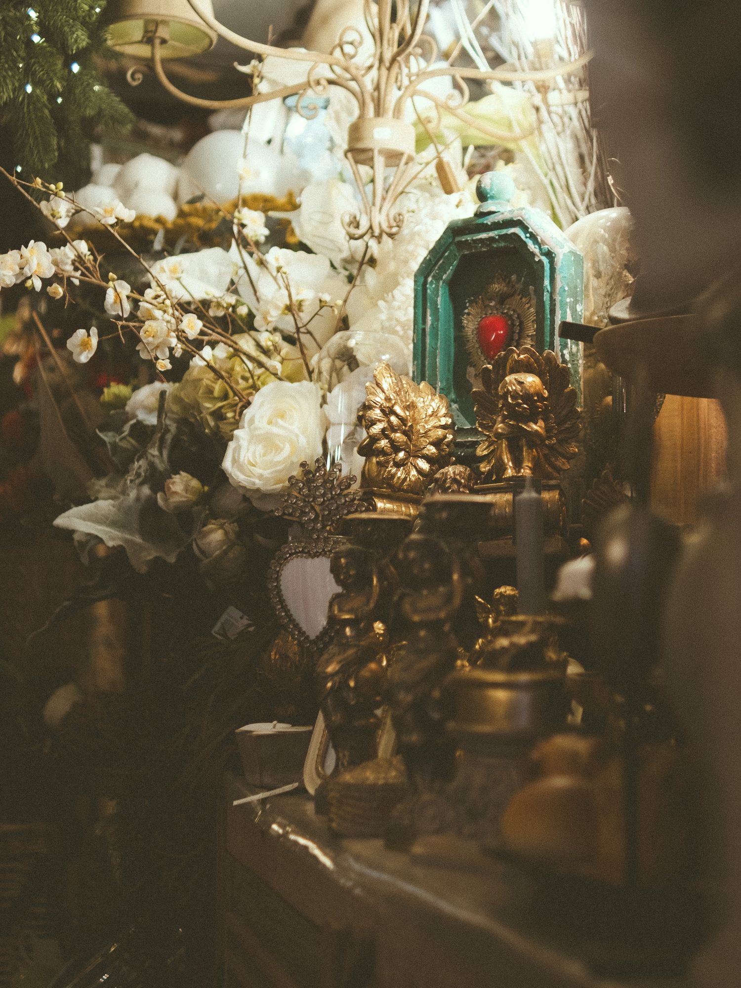 Gold figurines and white roses arranged with a teal ornate frame in a decorative vintage display.