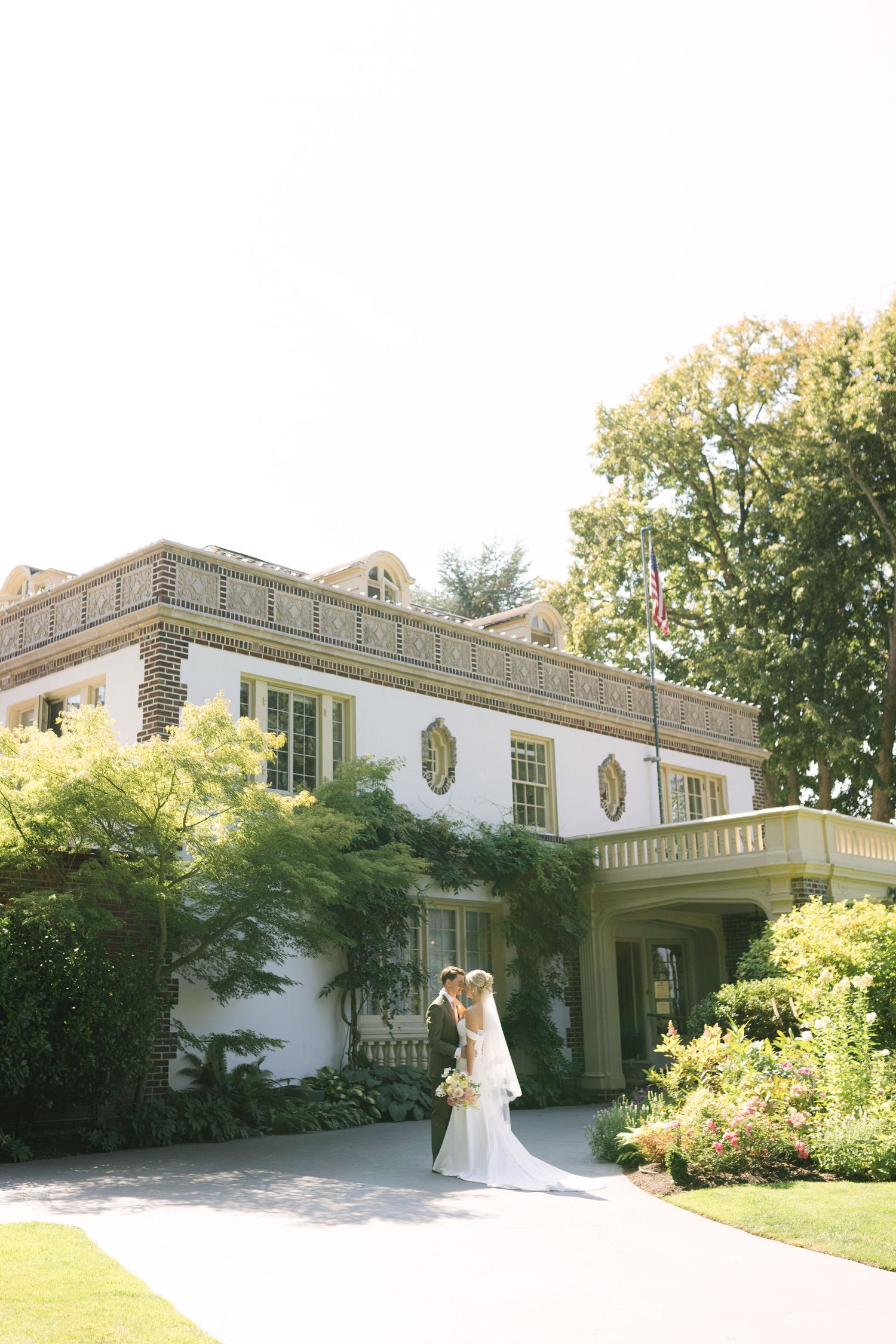 Elegant white mansion wedding venue with classical architecture and manicured gardens.