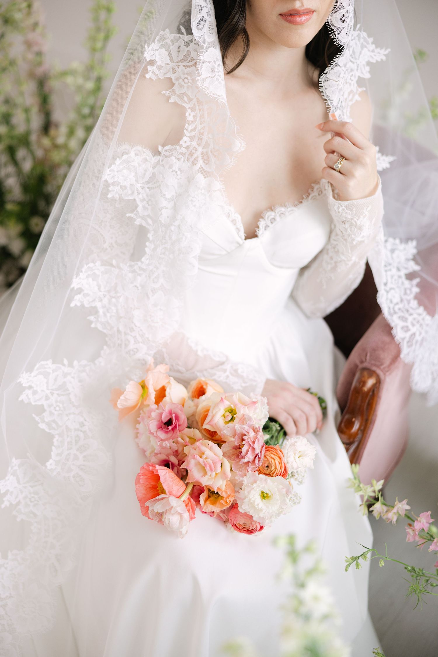 Beautiful bridal portrait with coral and peach roses against soft floral backdrop.