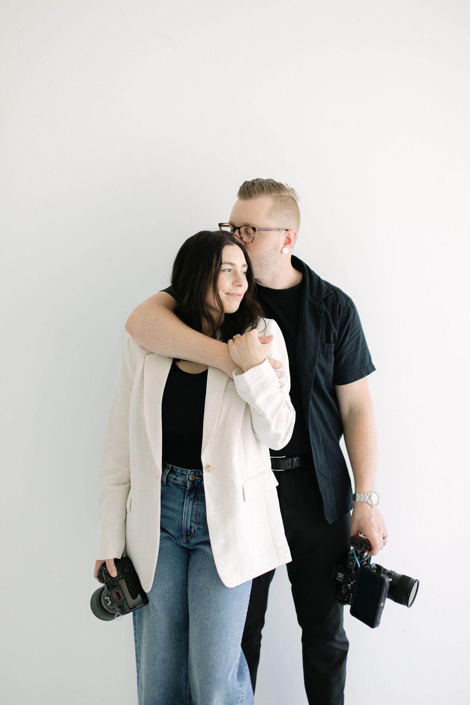 A couple in casual attire poses against a white wall in a series of playful candid shots.