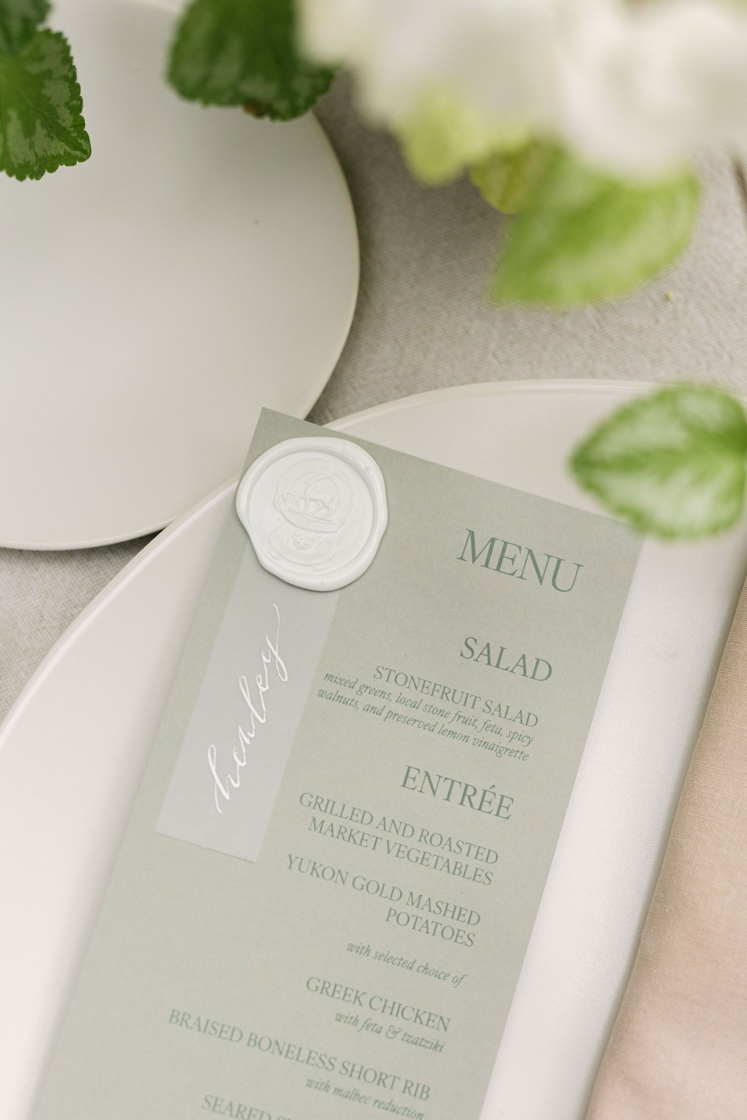 Elegant wedding menu cards with sage green text displaying salad and entree options.