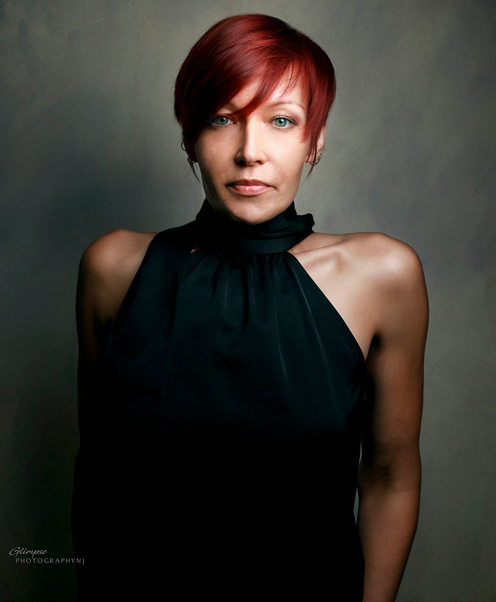 Woman with short red hair in black halter top poses for studio portrait photography.