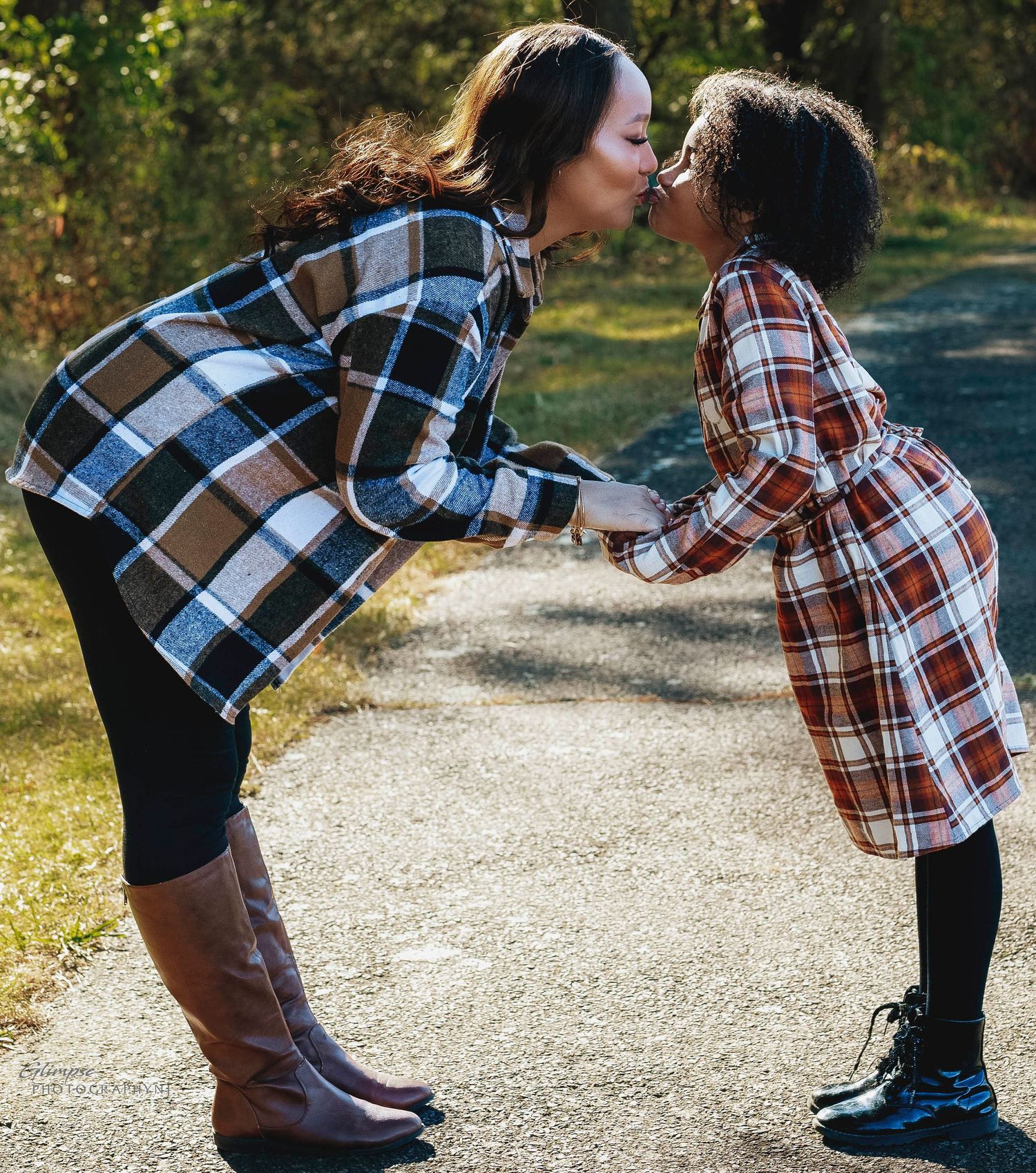 mother and daughter holding hands and kissing in the park on a fall day