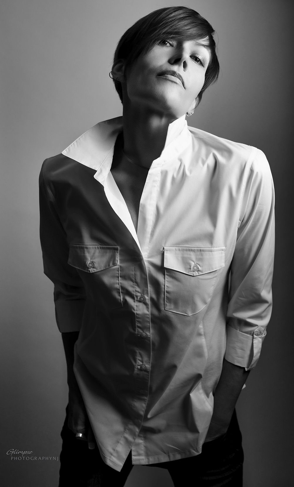 Black and white portrait of a woman in an open white button-down shirt looking upward.